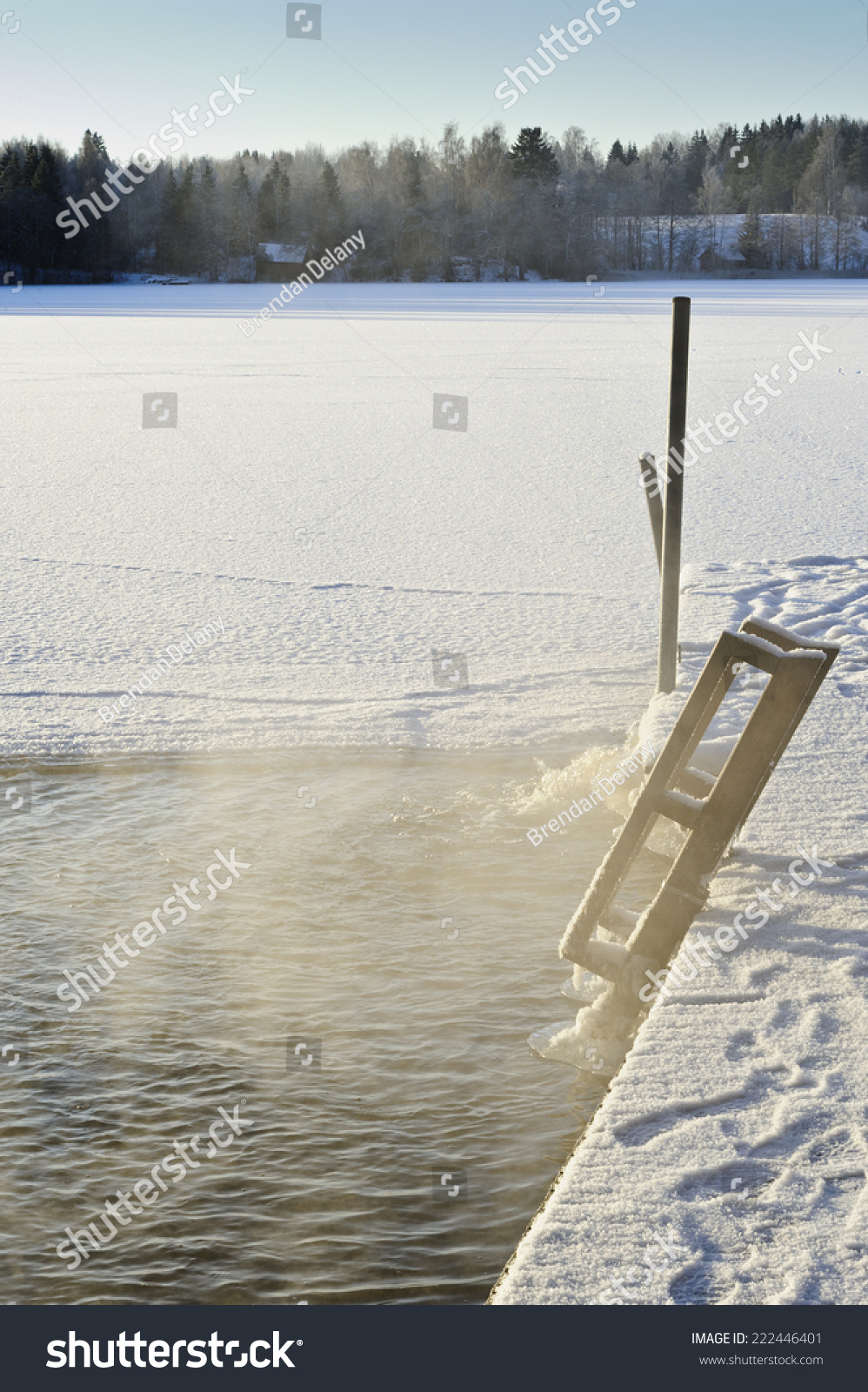 Hole in the lake ice for ice swimming. Pump visible towards end of jetty keeps water open. Footprints and ski tracks visible. The temperature is below -20 C creating a particular atmosphere