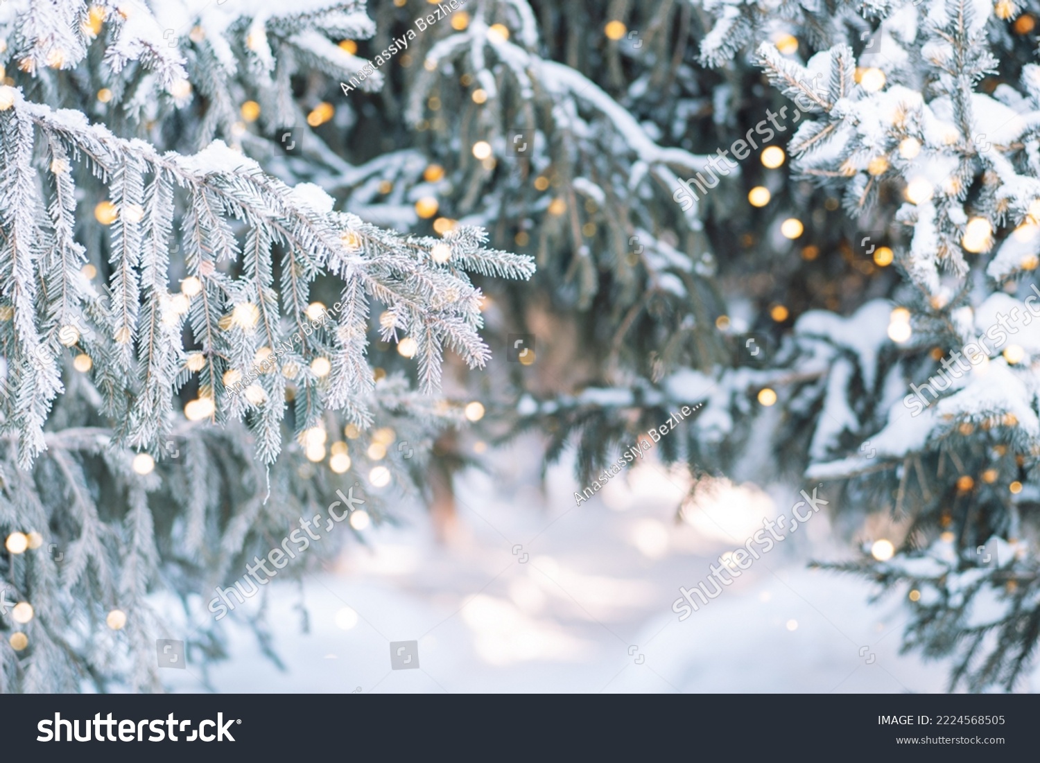 Outside Christmas tree in snow background with lights from garlands.