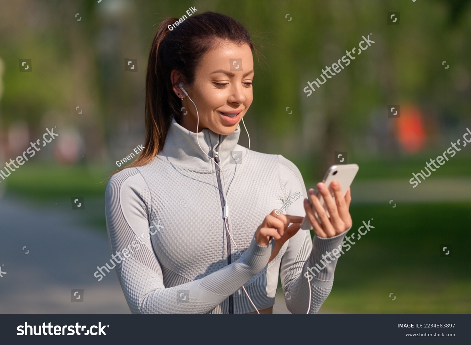 Young woman jogging. She seting up the music on her smartphone for a good jogging mood. The concept of keeping yourself in good shape.