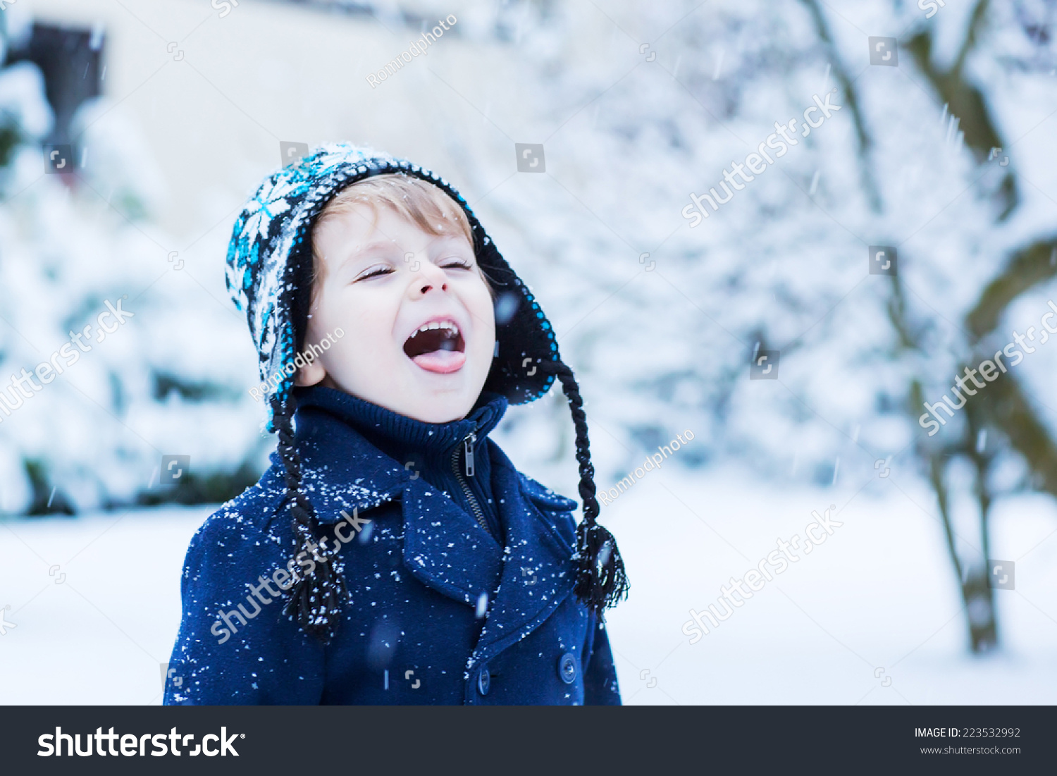 Portrait of Little toddler boy in winter clothes with falling snow