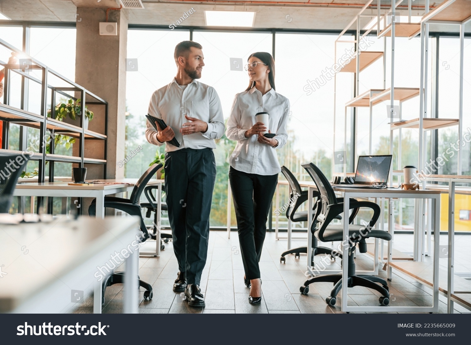 Front view. Man and woman are working in the modern office together.