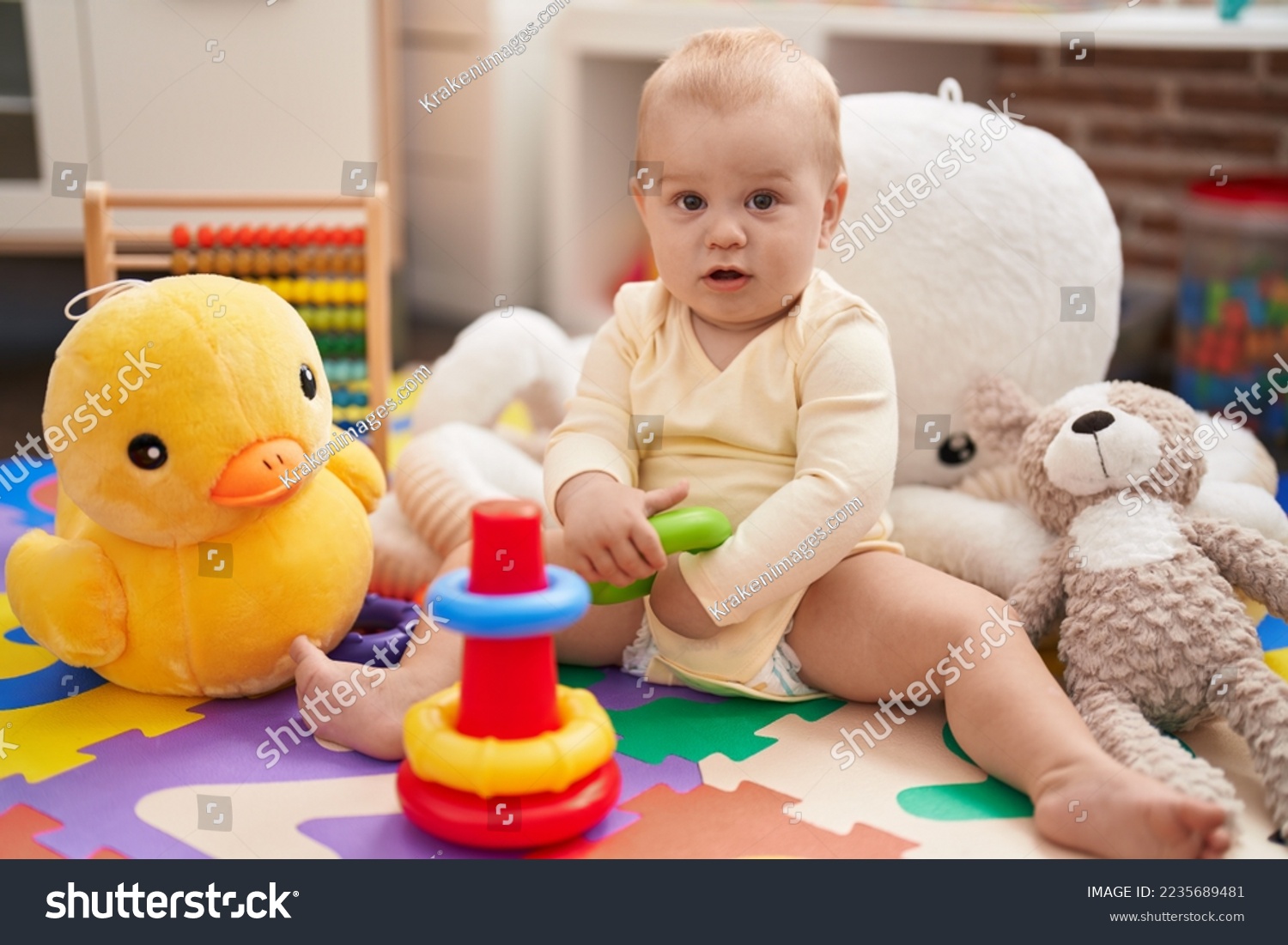 Adorable caucasian baby playing with hoops toy sitting on floor at ...