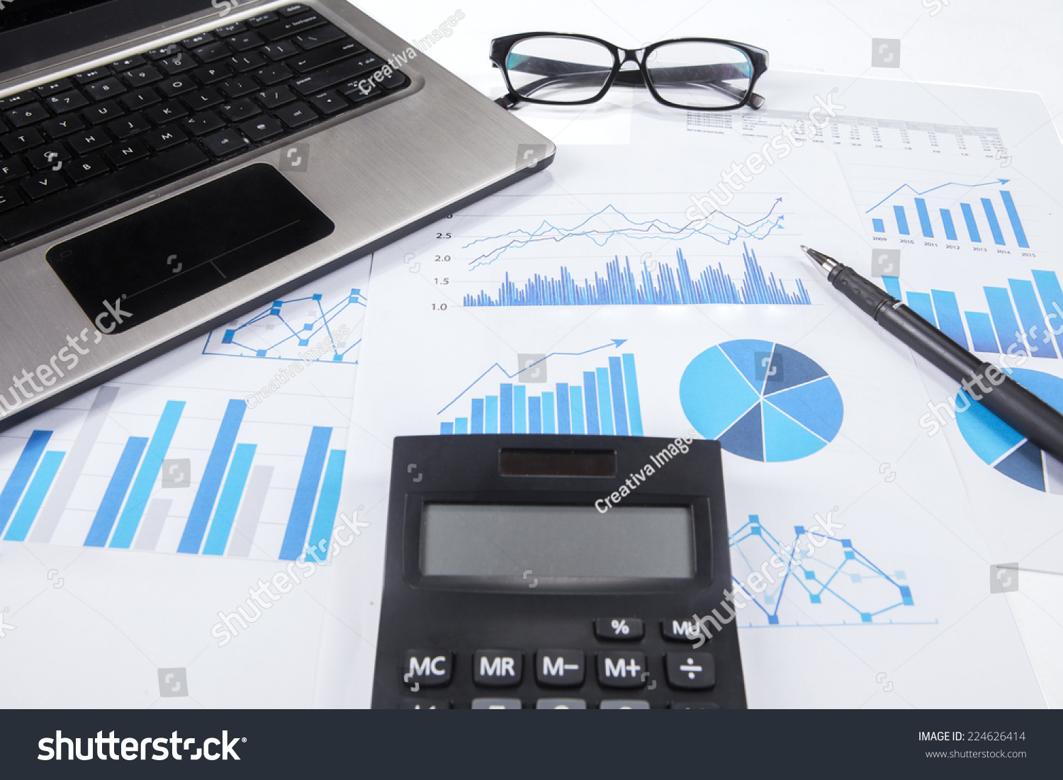 Closeup of calculator on business chart with pen  laptop  and glasses