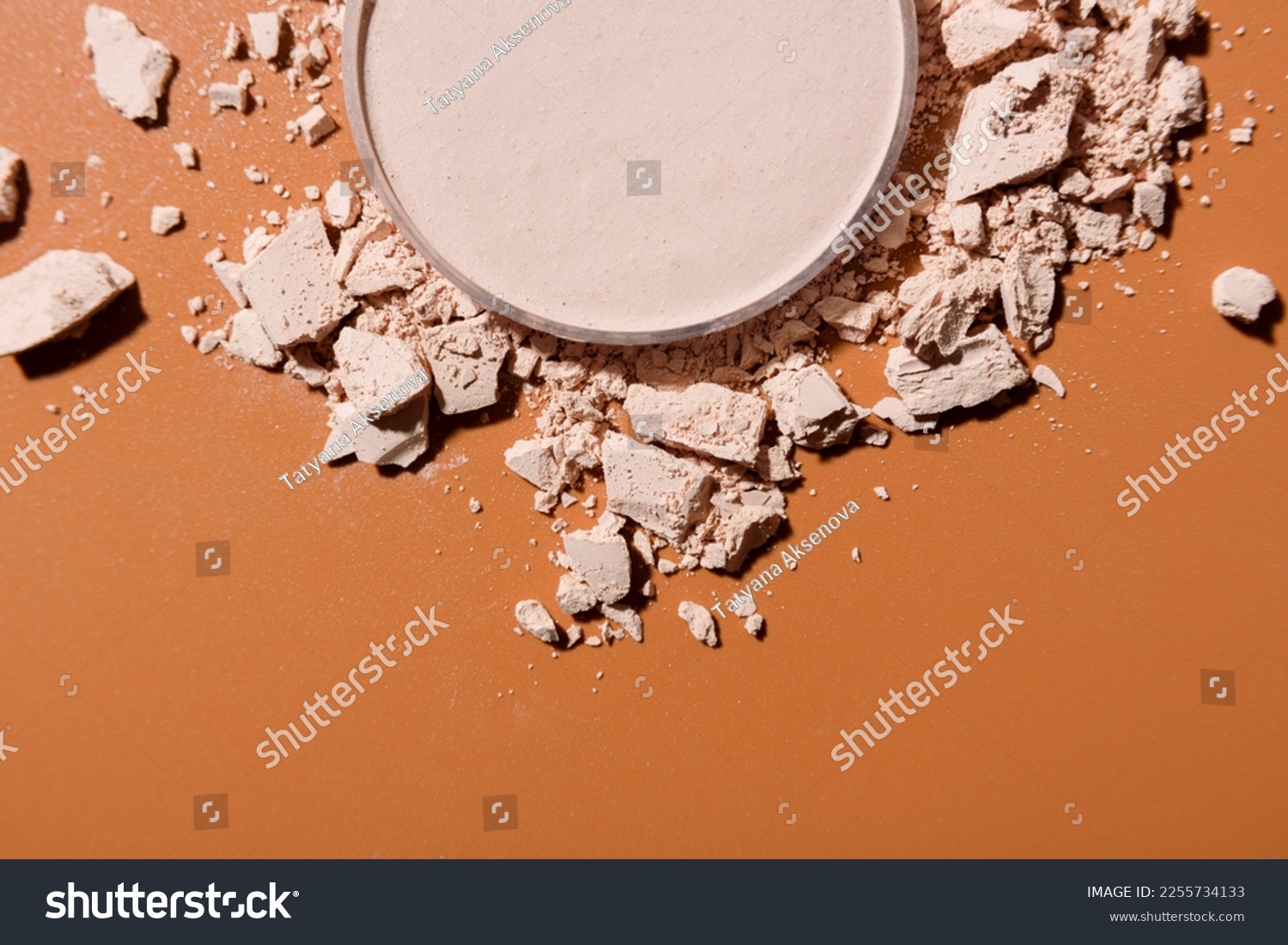 Crushed face powder heap and round box of pressed one on top on brown background  close up