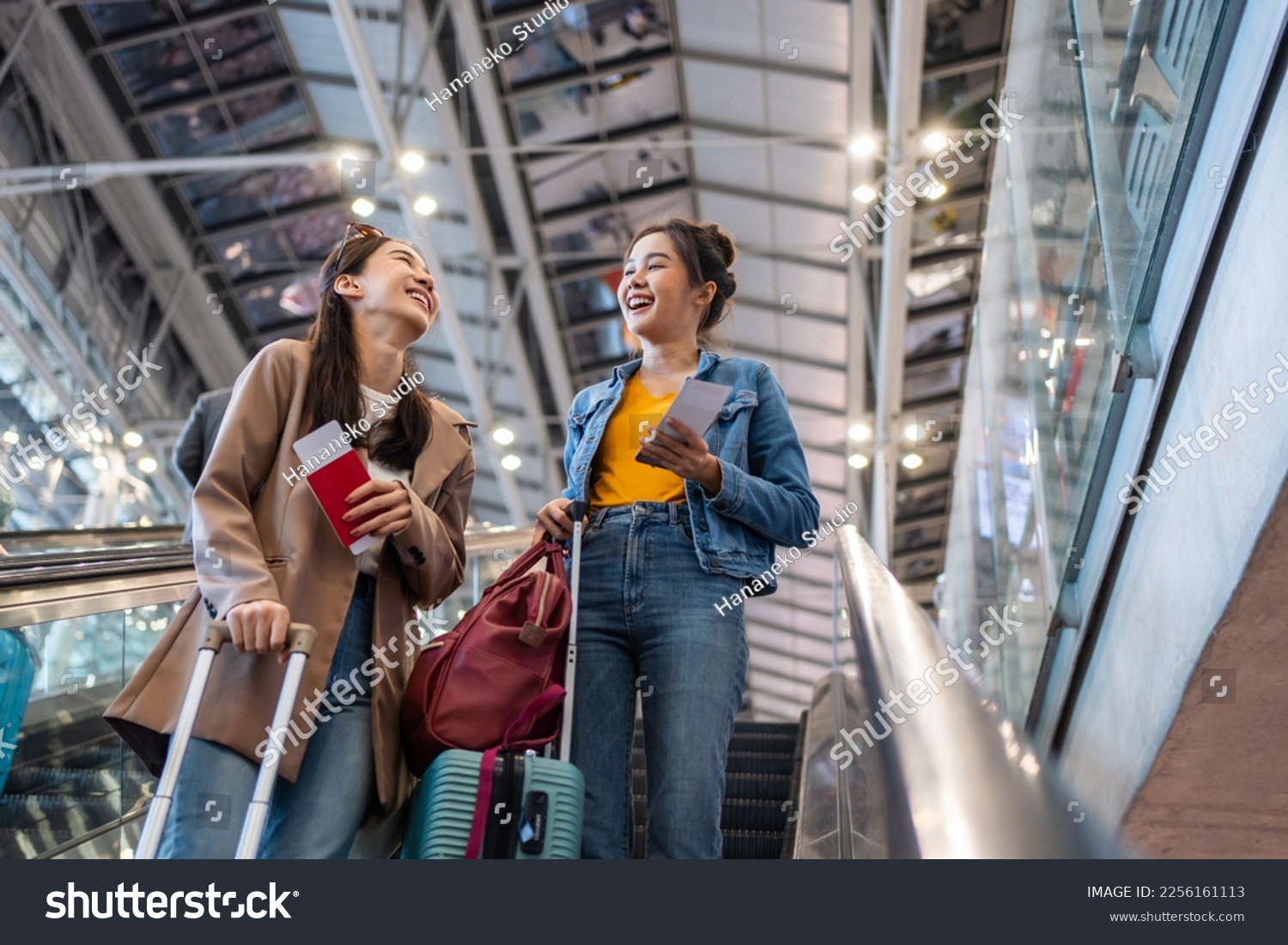 Asian young women passenger walk in airport terminal to boarding gate. Attractive beautiful female tourist friends feeling happy and excited to go travel abroad by airplane for holiday vacation trip.