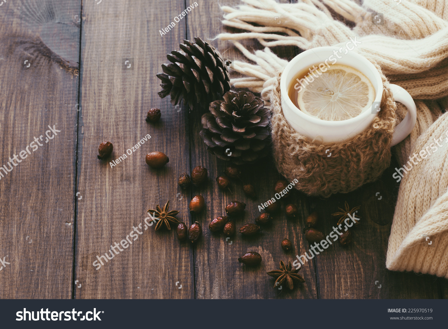 Cup of hot tea with lemon dressed in knitted warm winter scarf on brown wooden tabletop top view point