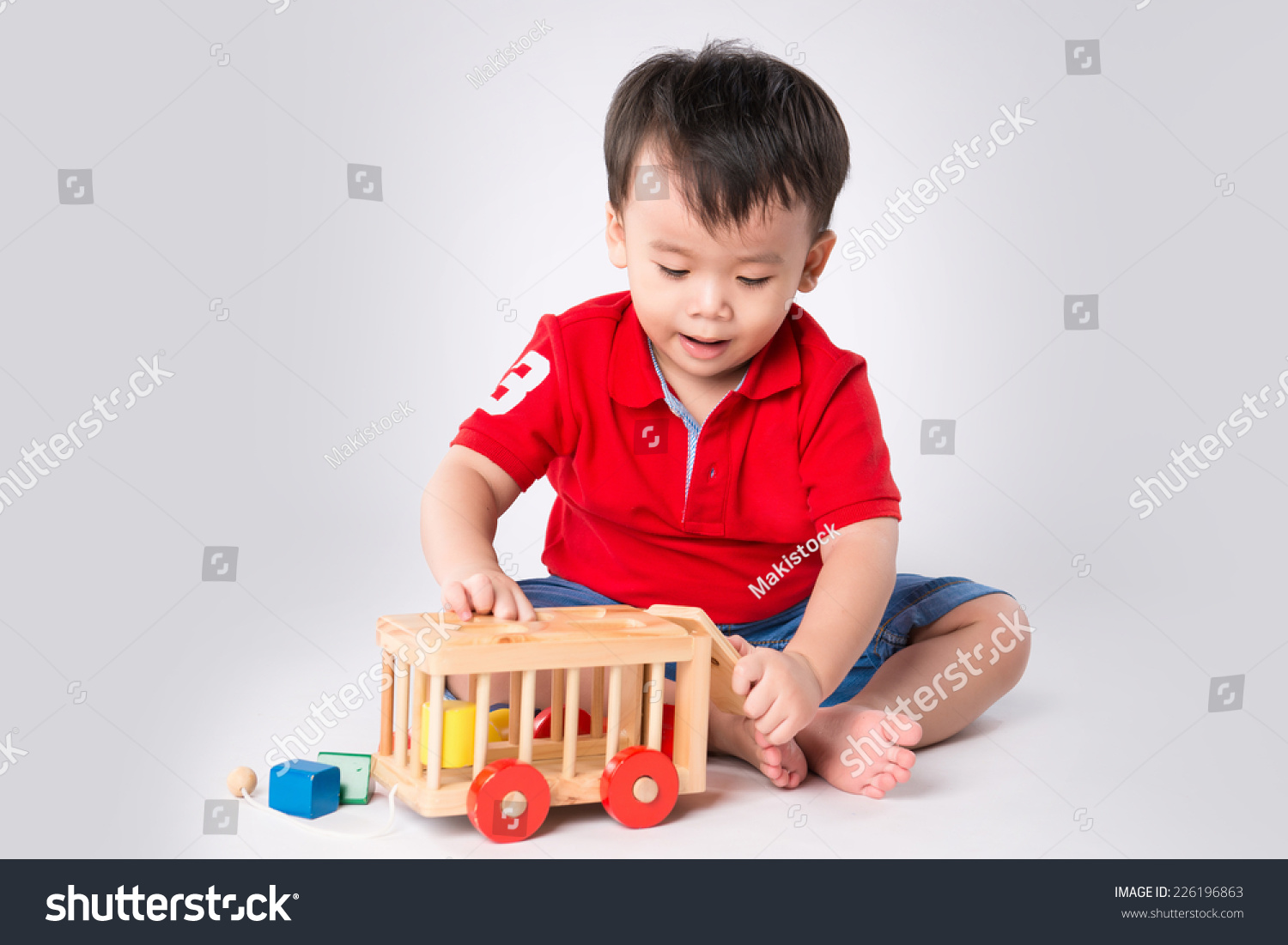 Asian boy playing with the small colorful wooden car. Little boy playing with cubes  smiling.