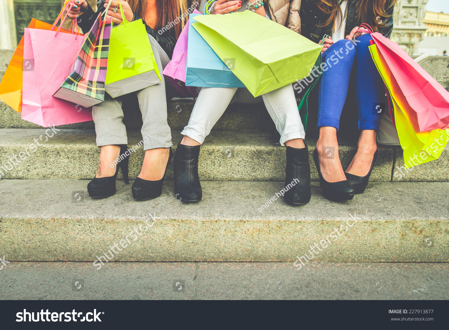 Women with high heels and shopping bags - Three girls sitting on stairs and chatting after buying presents