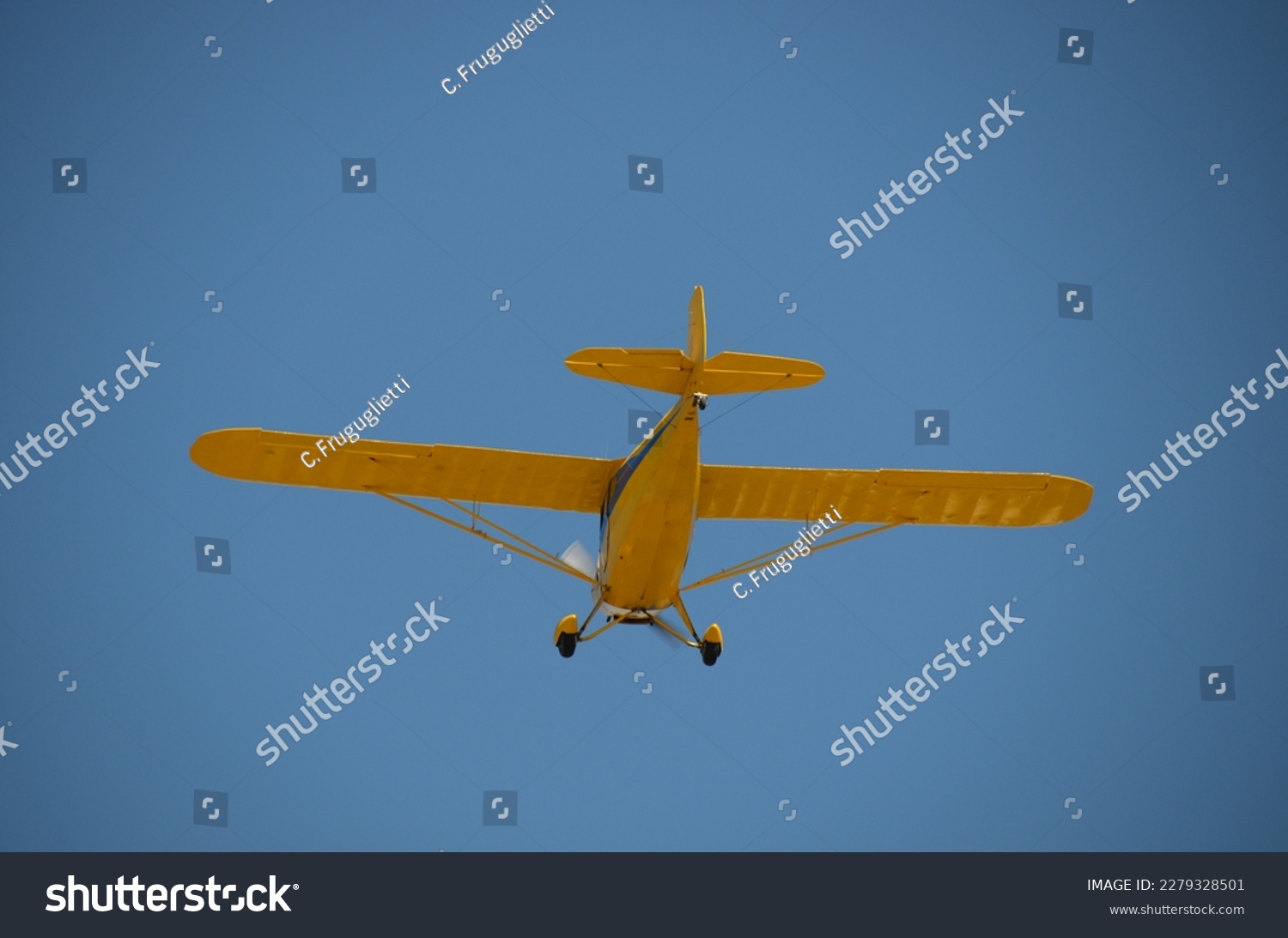 Cool picture of an old yellow tail wheel airplane as it flies away.