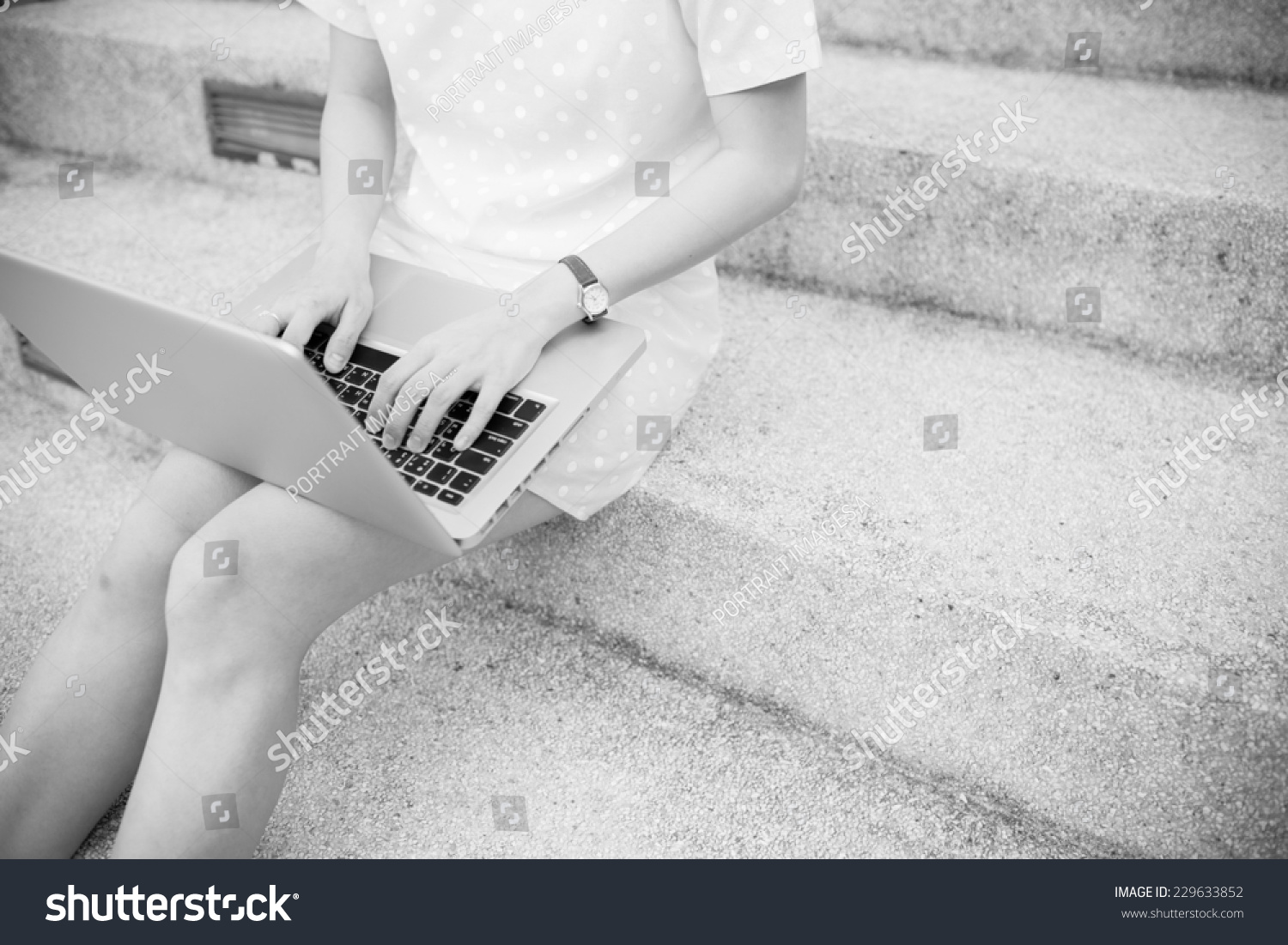 Young woman using laptop on steps outdoors