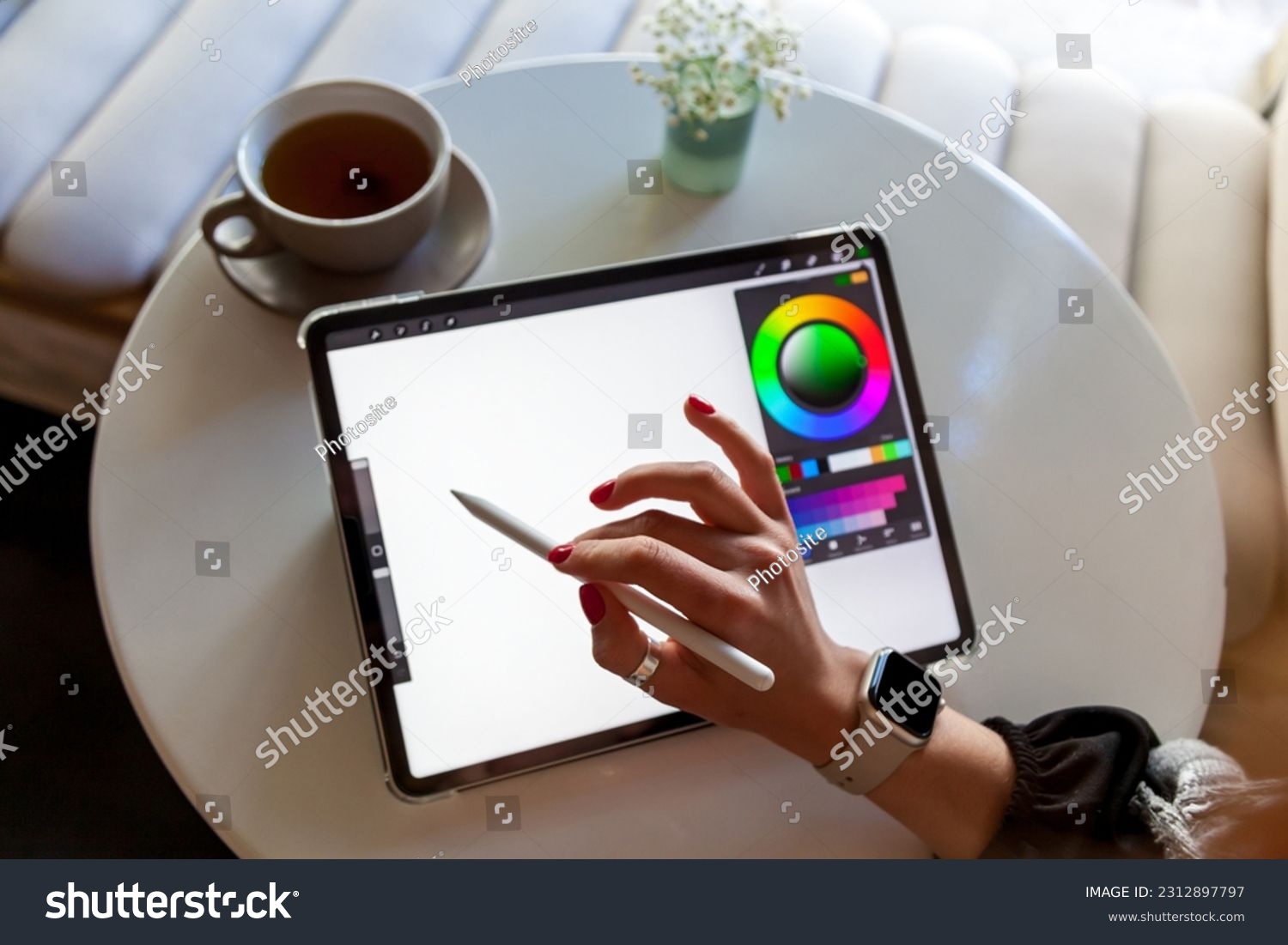 A girl in a cafe draws with a stylus on a graphics tablet.Remote work ...