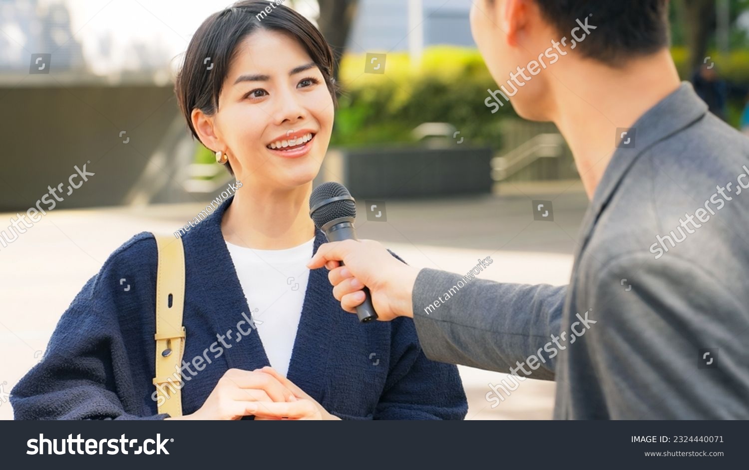 Asian woman being interviewed on the street. TV broadcasting ...