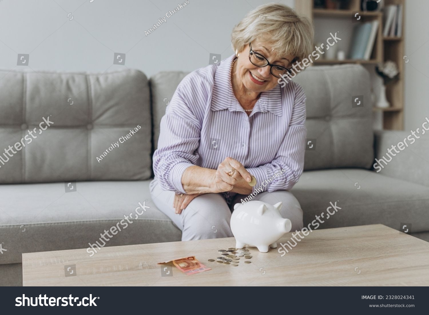 savings money annuity insurance retirement and people concept - smiling senior woman putting coins into piggy bank at home