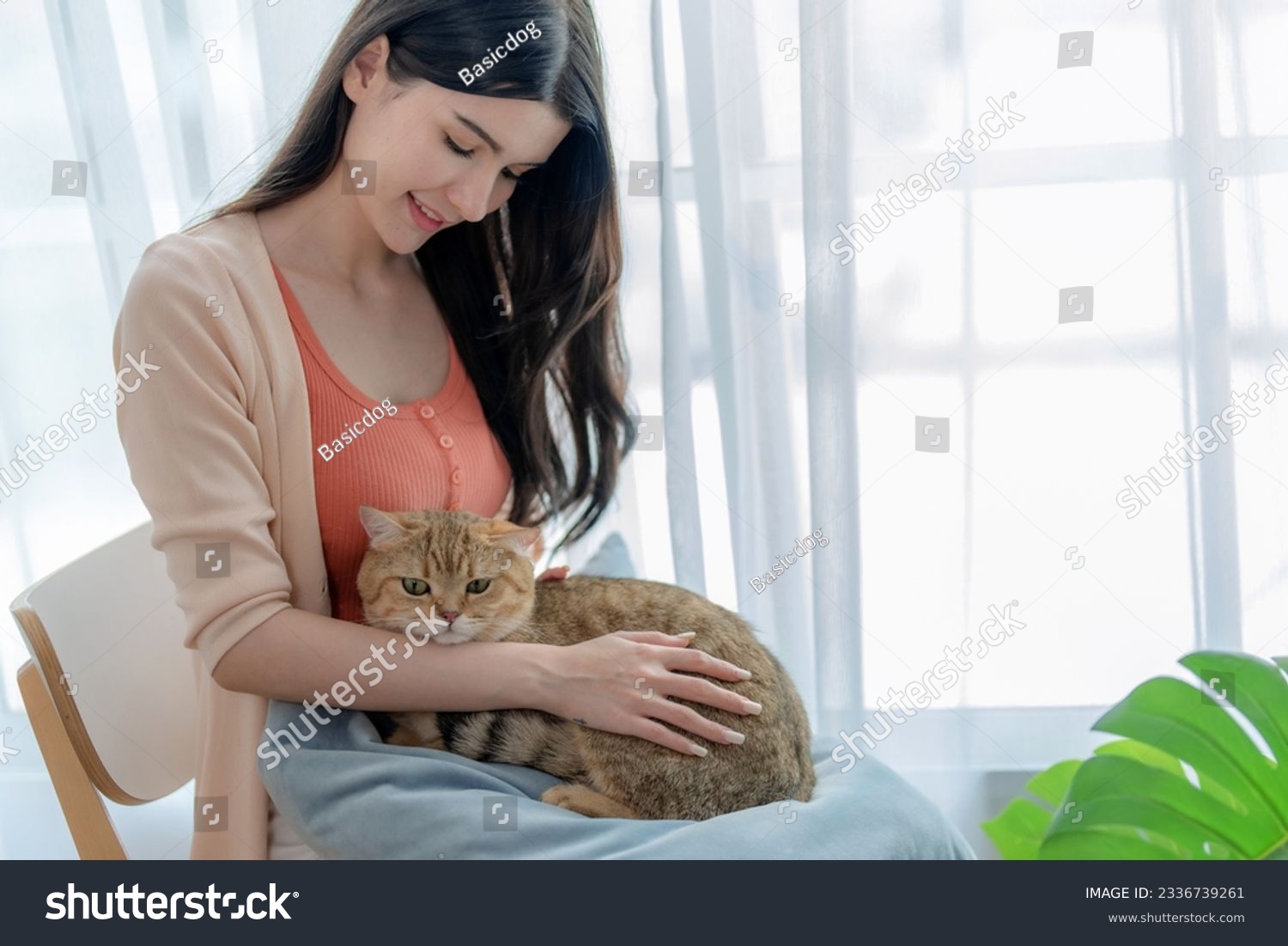 Beautiful young woman spends her free time on vacation playing with her beloved pet at home.