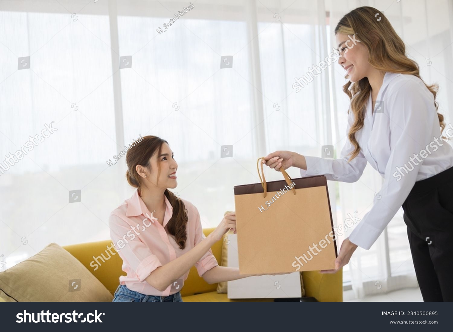 Happy Asian Salesperson Giving Shopping Bag to Satisfied Woman Customer at Trendy Retail Store - Consumerism and Shopping Concept