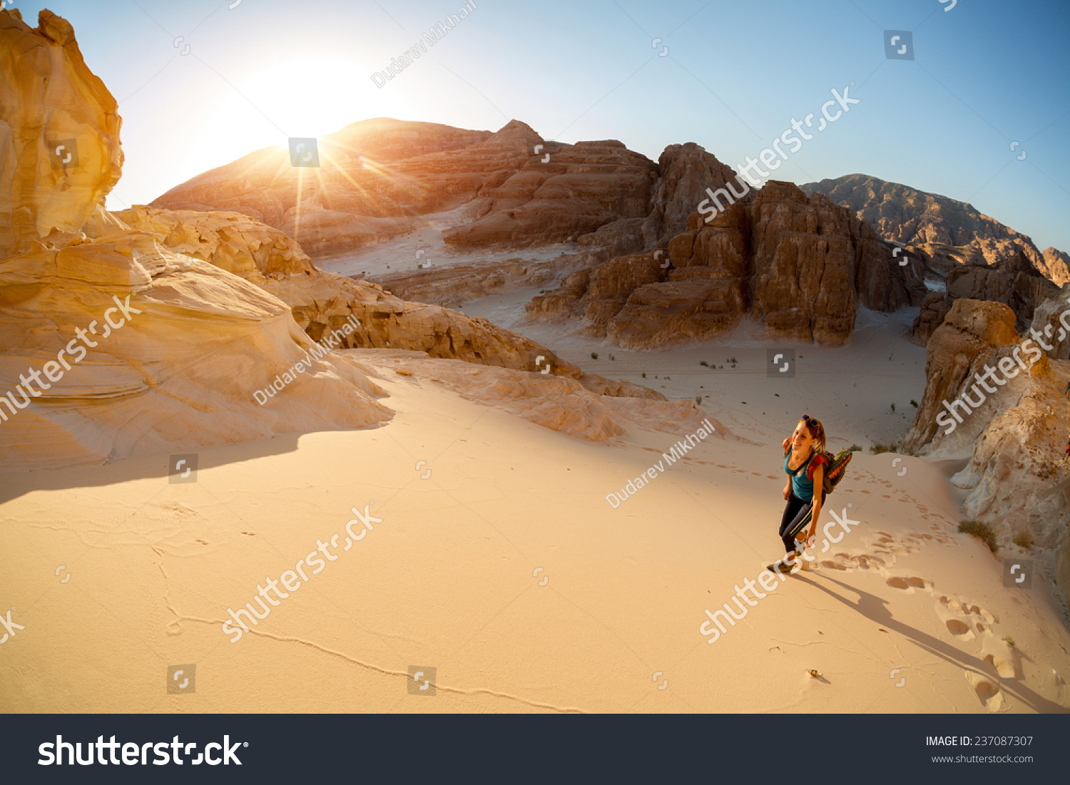 Hiker walking on sand in the desert with valley on the background