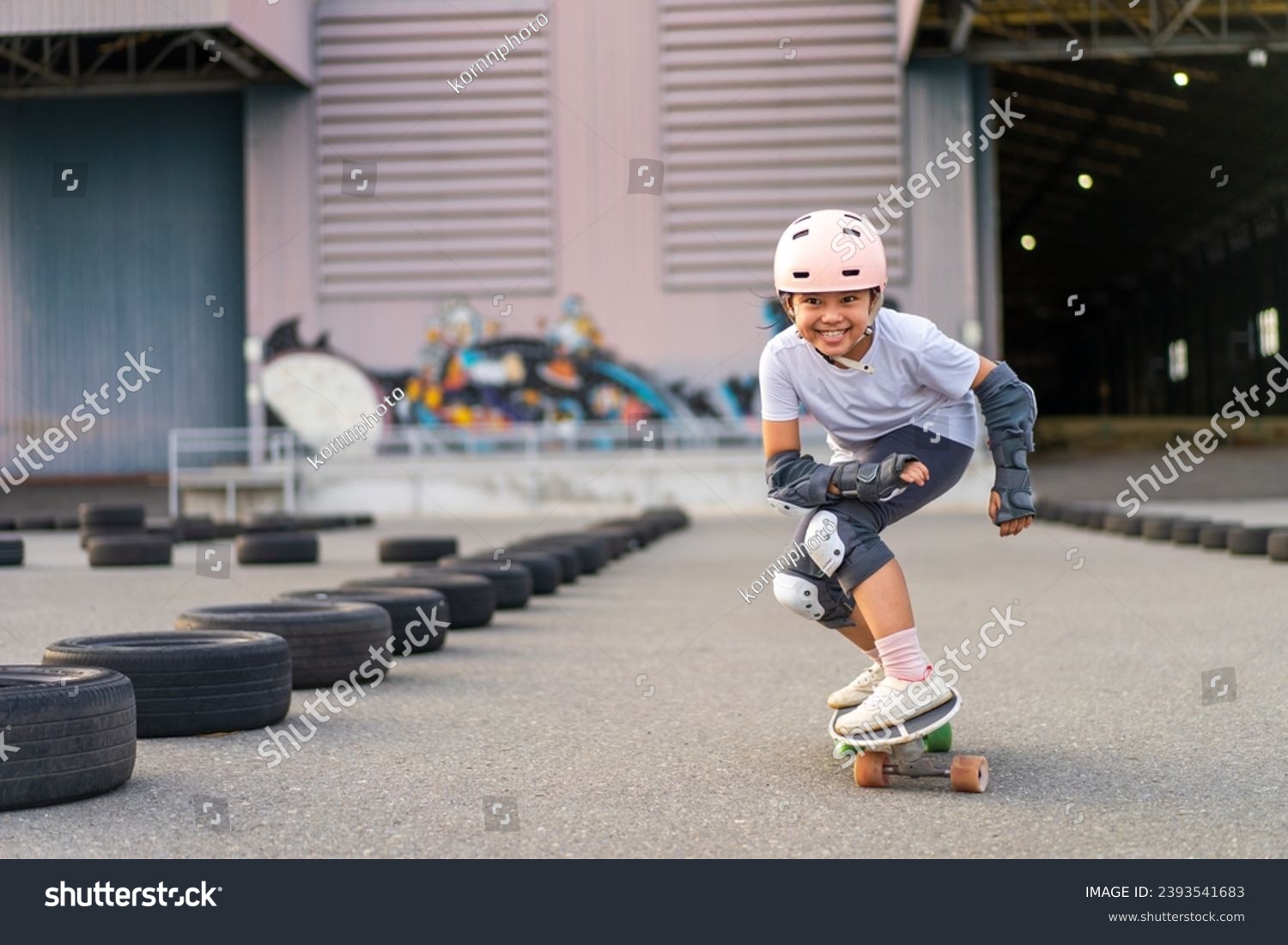 asian child skater or kid girl fun playing skateboard or enjoy riding carving surf skate on car tires track in skatepark lane to smile for extreme sports exercise and wears helmet guard to body safety