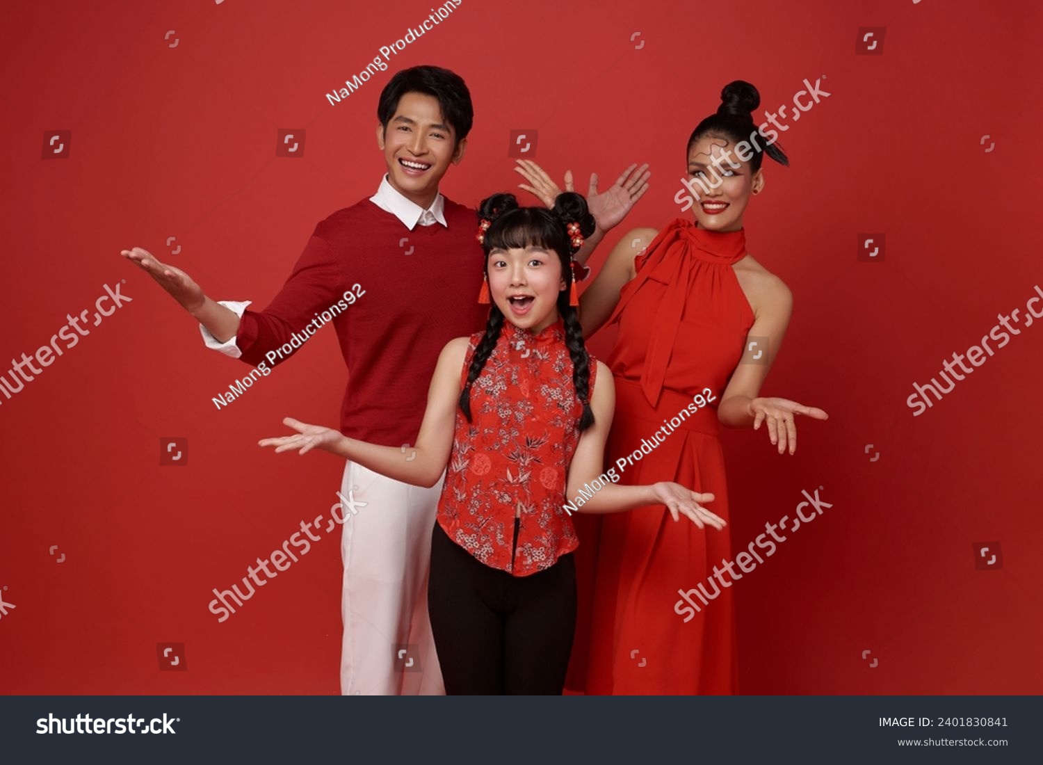 Happy asian family wearing red costume presenting or showing open hand palm with copy space for product isolated on red background. Present product advertising concept.