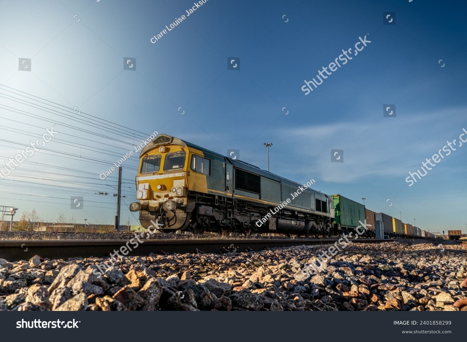 Profile view of a goods train with Intermodal wagons full of shipping container boxes for import and export in a yard or sidings