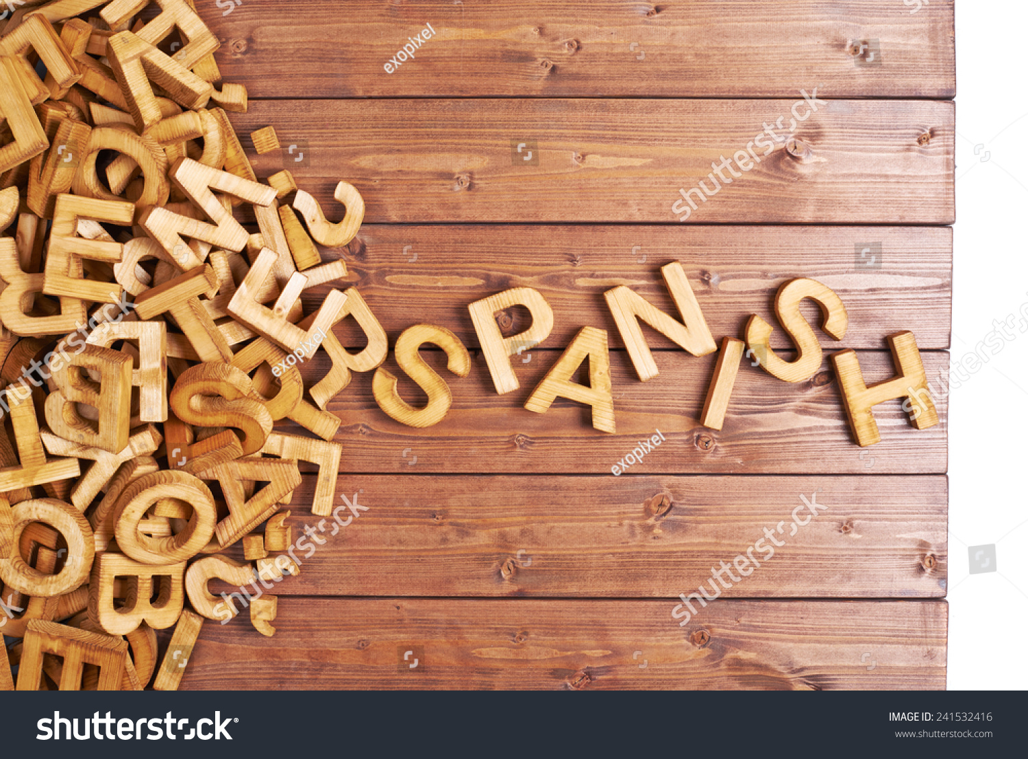 Word spanish made with block wooden letters next to a pile of other letters over the wooden board surface composition