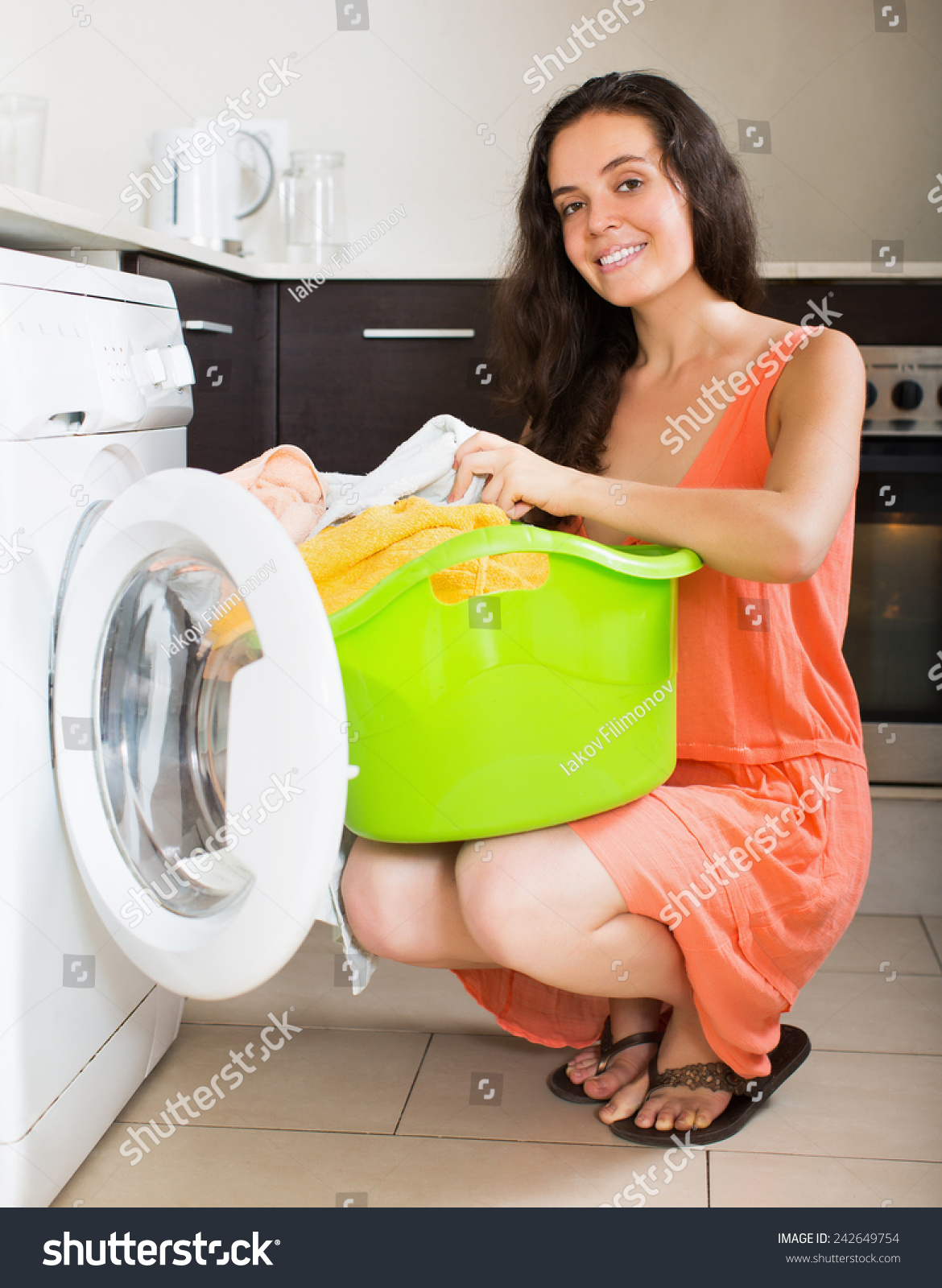 happy woman cheking white clothes near washing machine