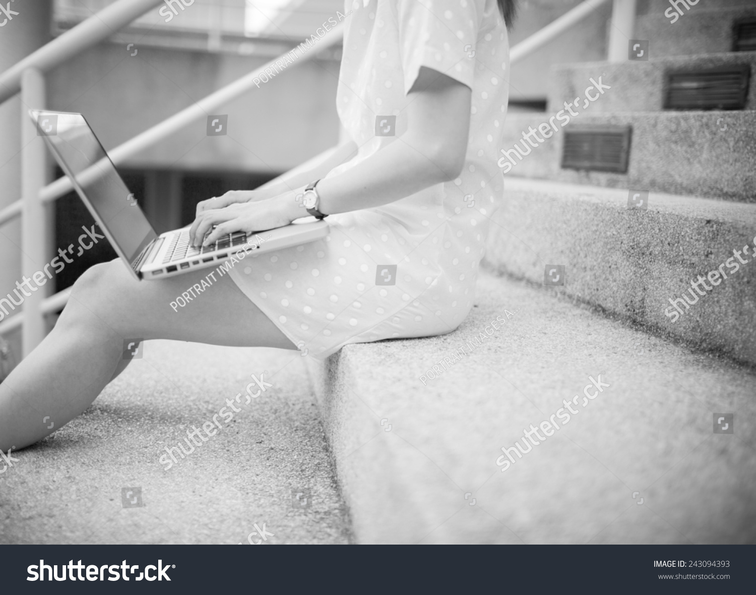 Young woman using laptop on steps outdoors