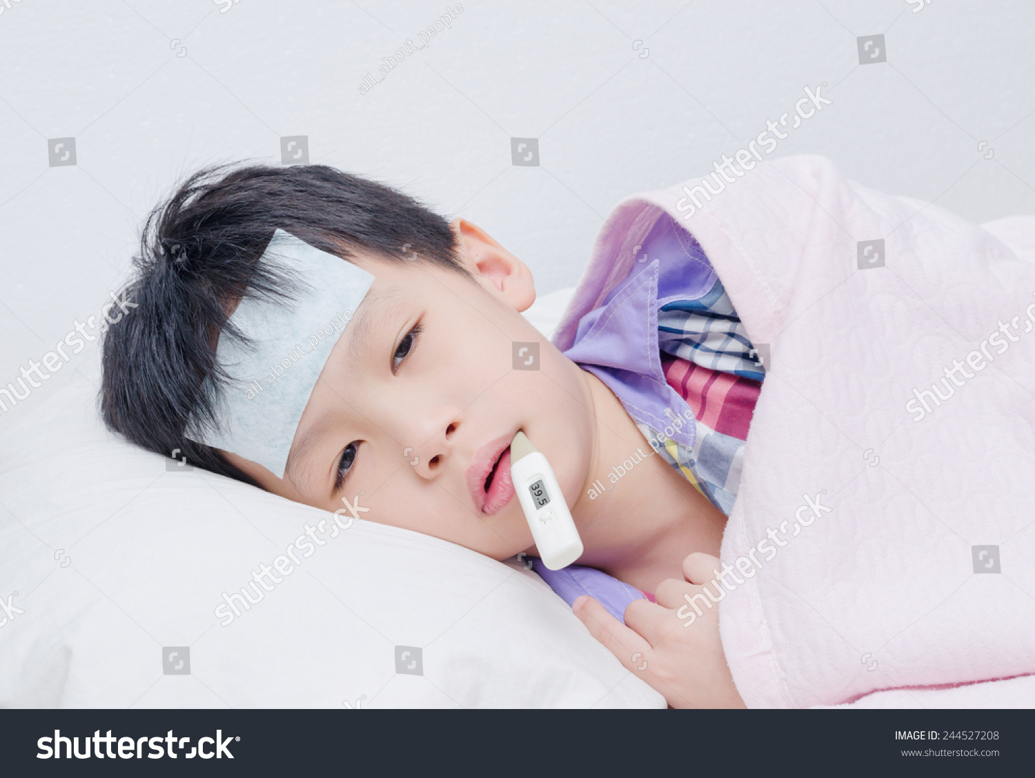 Little sick boy lying on bed with digital thermometer in mouth