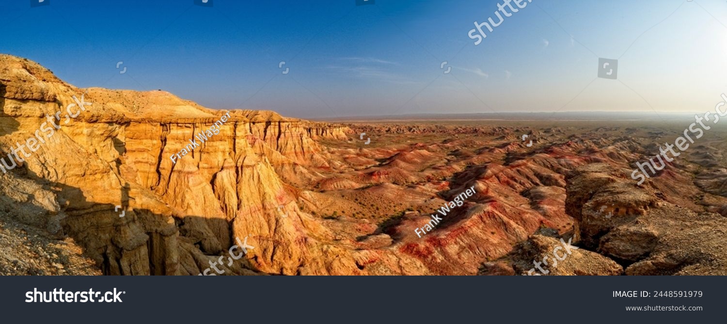 Panorama over the rock formations and cliffs of the so-called "White Stupa" a mountainous primeval landscape in the Gobi Desert Mongolia in the warm light of the rising or setting sun