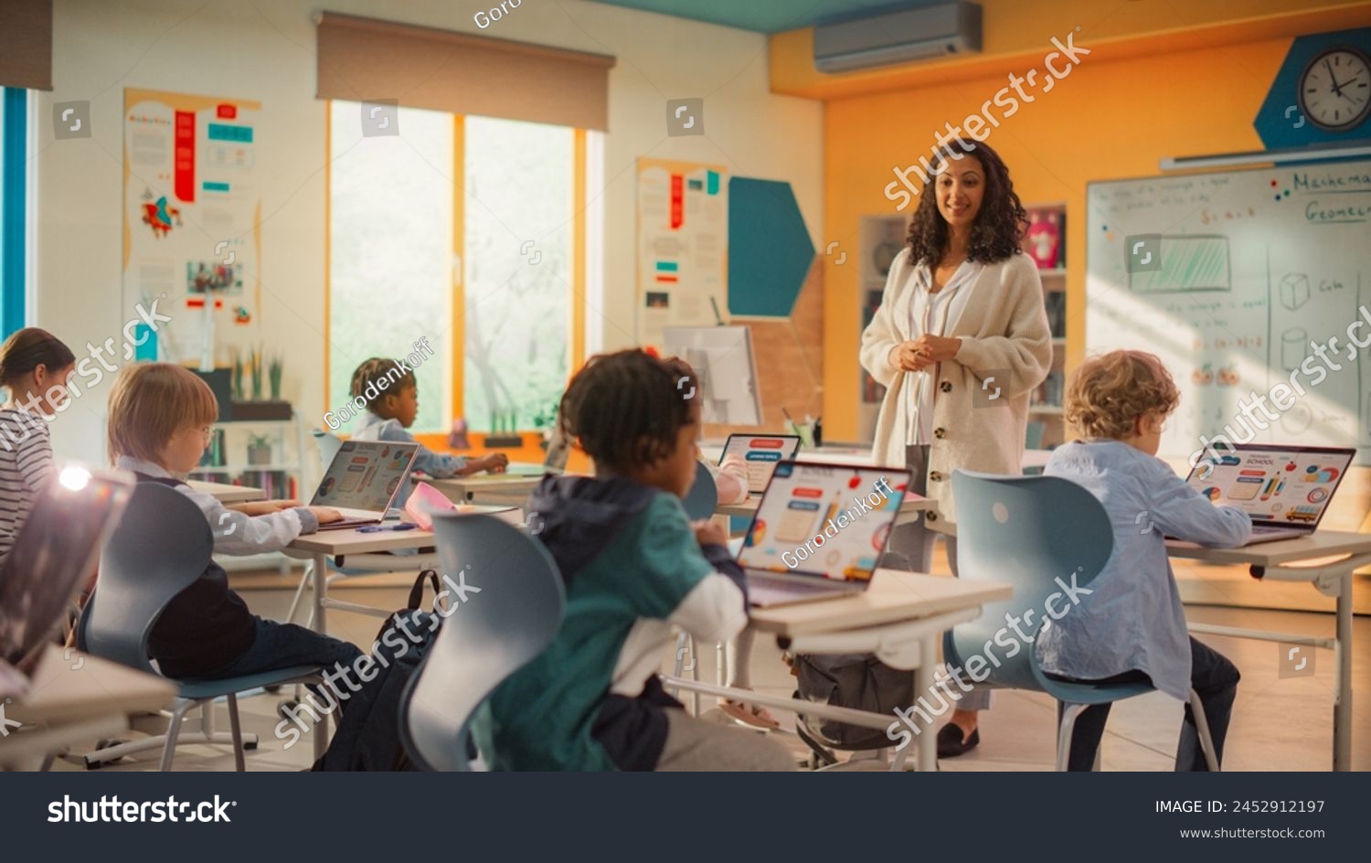 Elementary School Children Learning Basic Computer Skills: Teacher Educating Smart Diverse Kids in a Modern Colorful Classroom. Schoolchildren Getting Experience with Internet and Technology