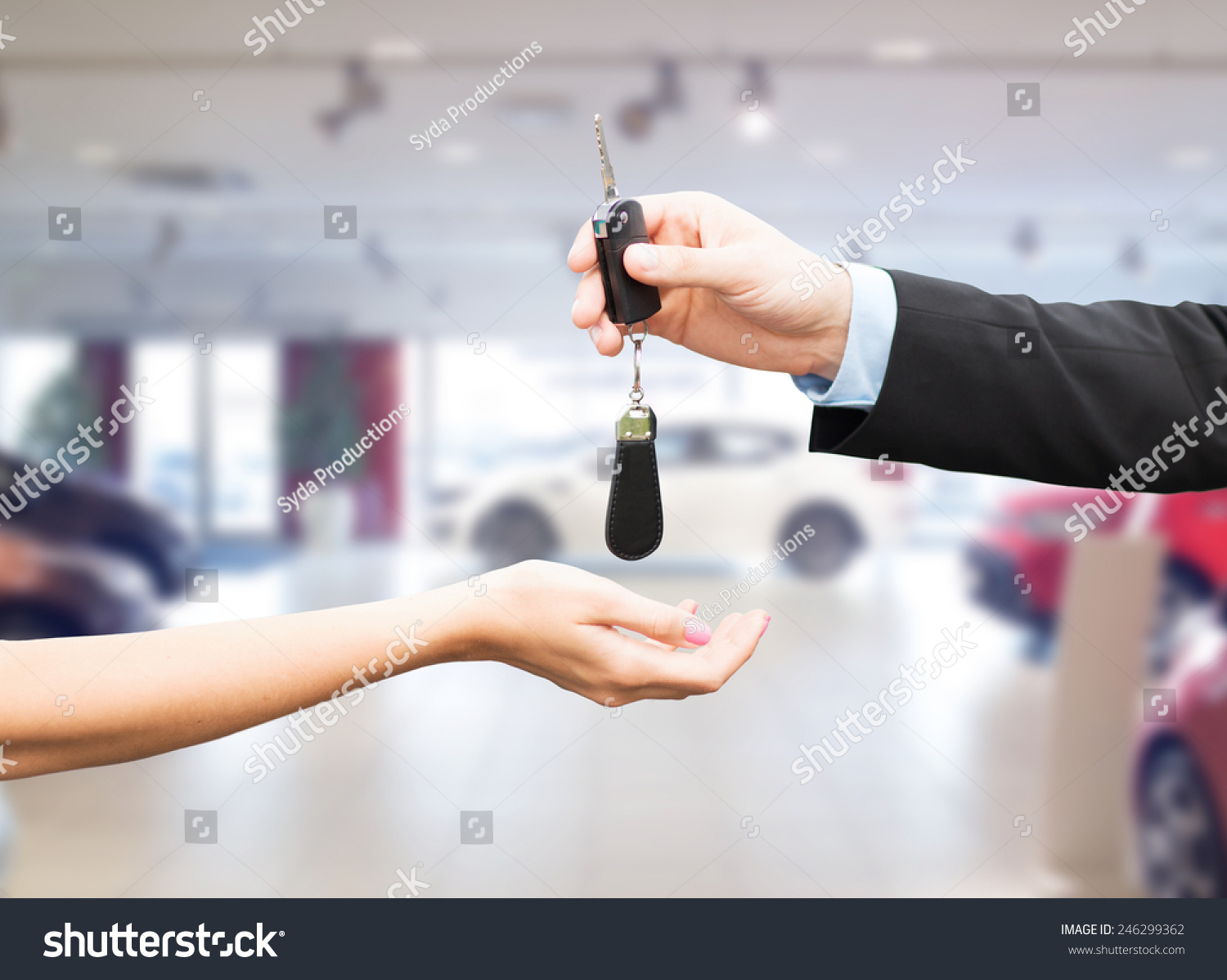 auto business car sale transportation people and ownership concept - close up of car salesman giving key to new owner or customer over auto show background