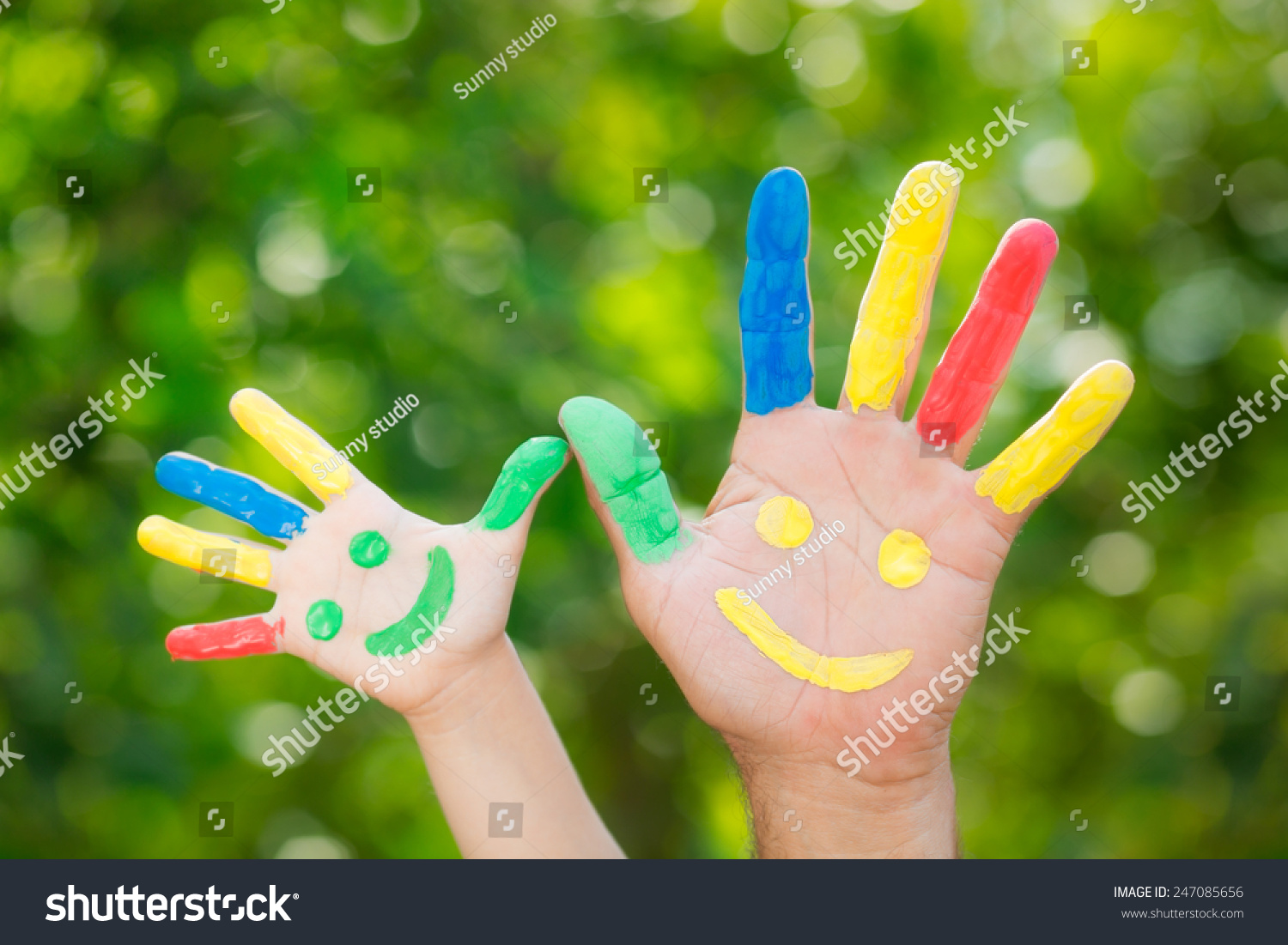 Smiley on hands against green spring background. Father and son having fun outdoors