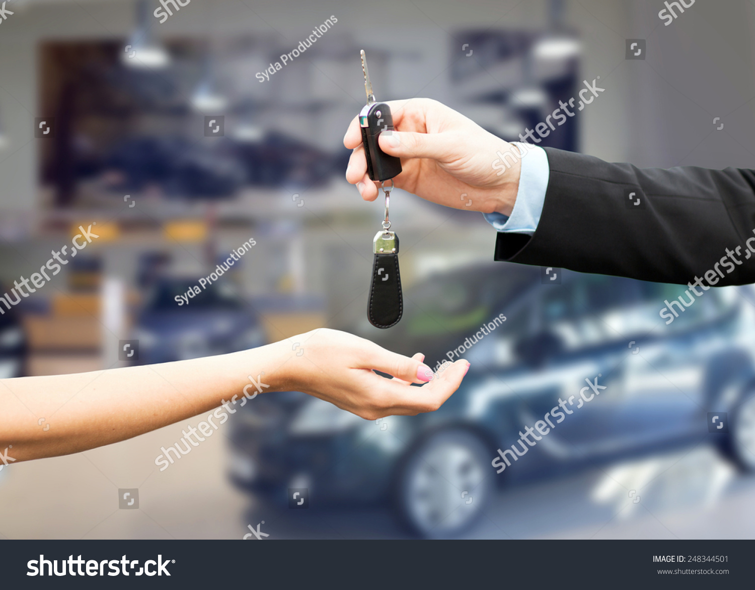 auto business car sale transportation people and ownership concept - close up of car salesman giving key to new owner or customer over auto show background