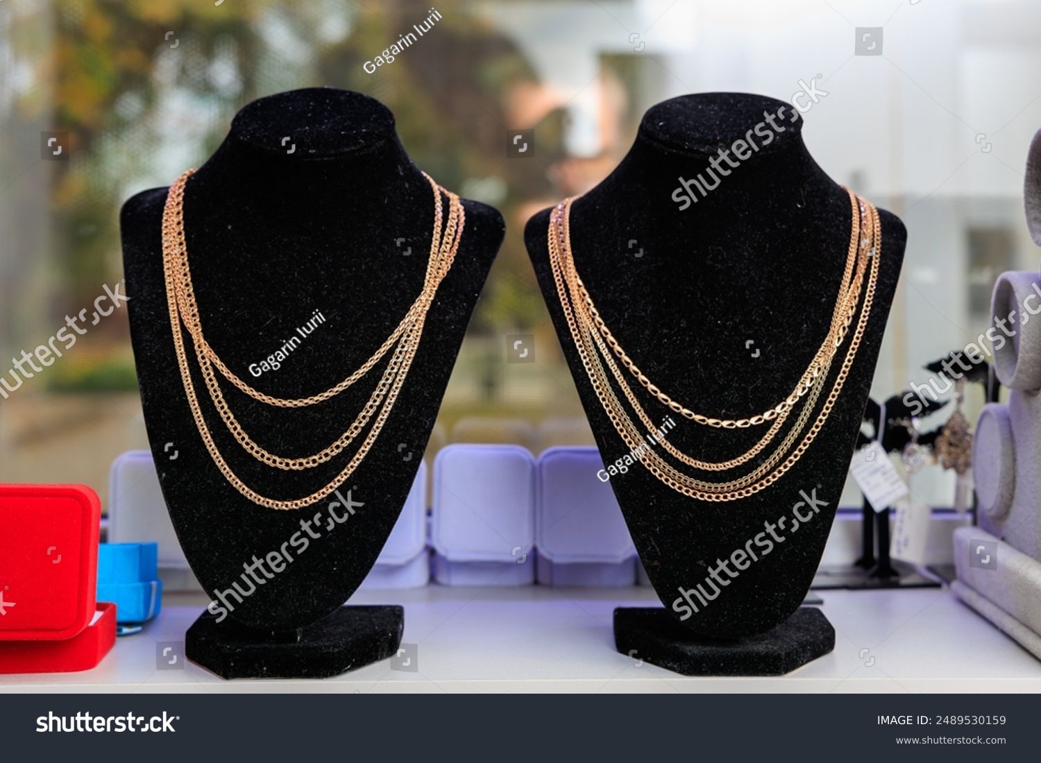 Two necklaces are displayed on a black stand. One necklace is a gold chain with a black pendant  jewelry pawn shop