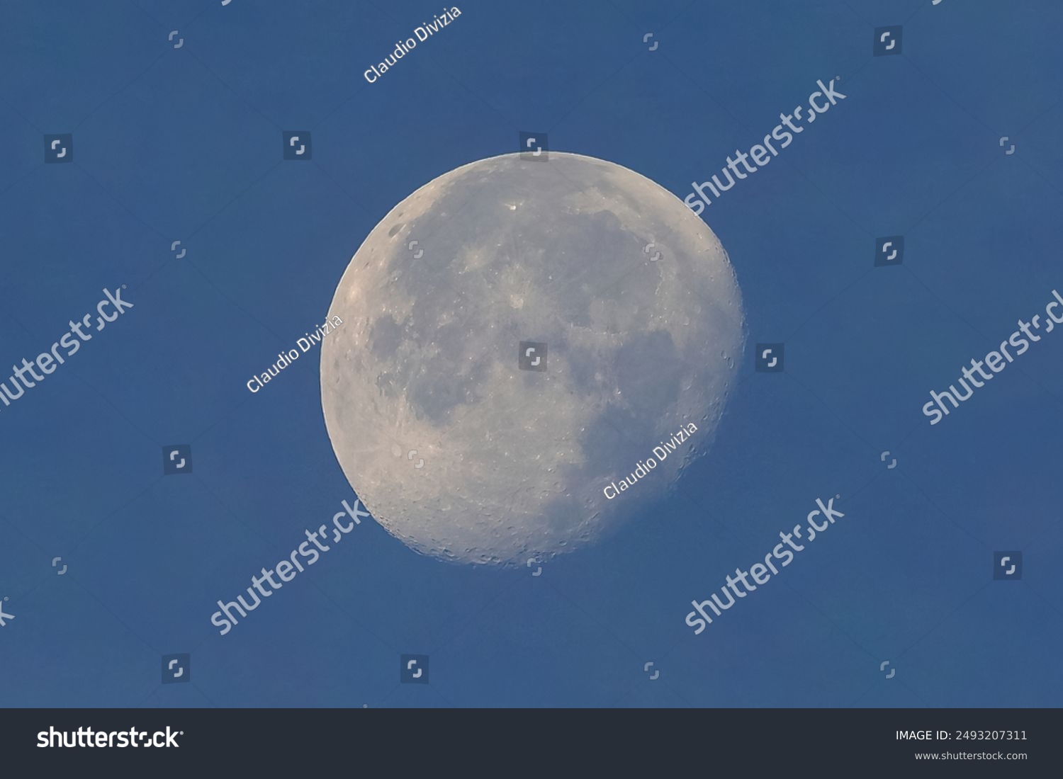Full moon seen with astronomic telescope over blue sky in the morning