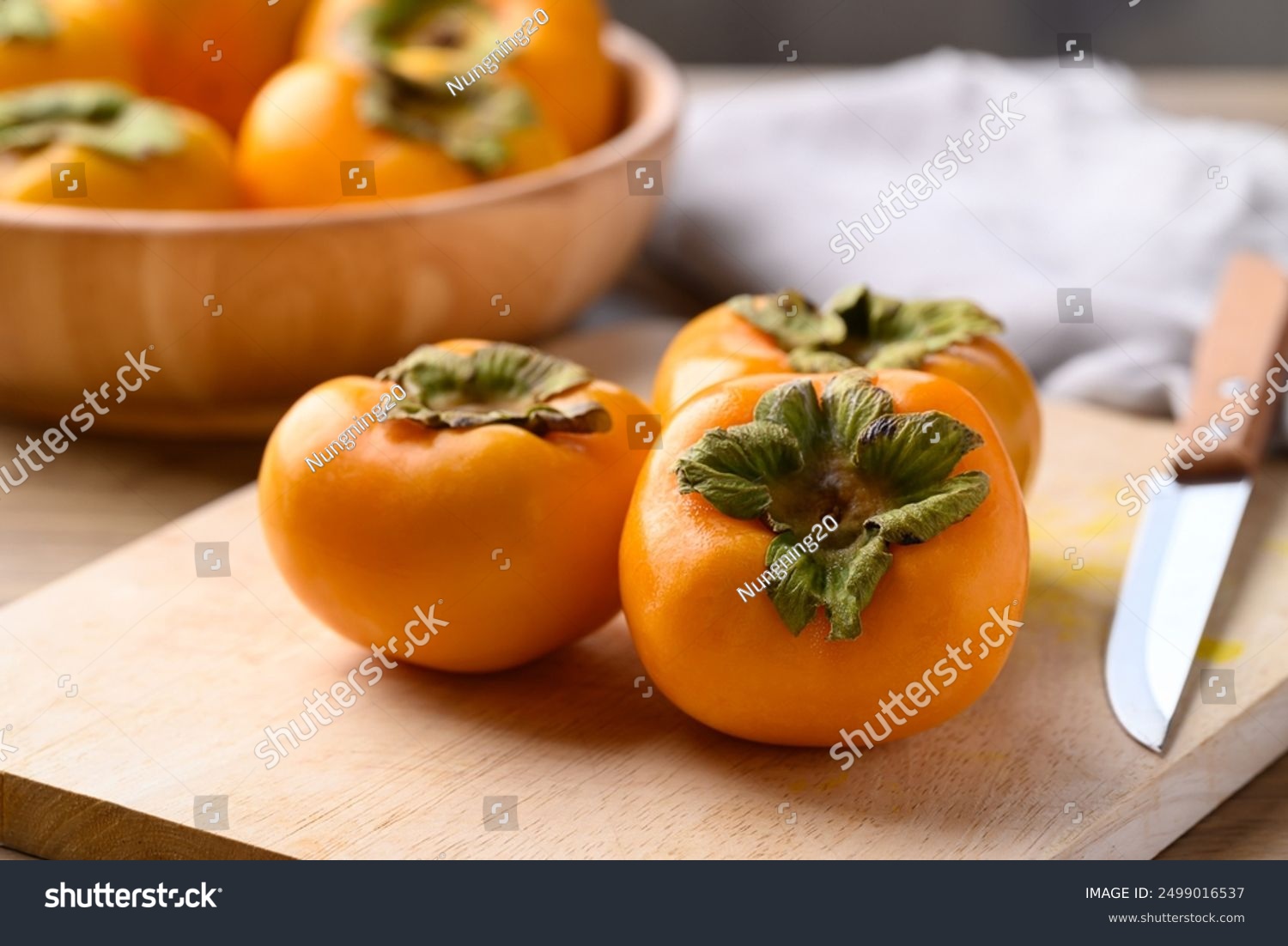 Ripe persimmon fruit on cutting wooden board with knife