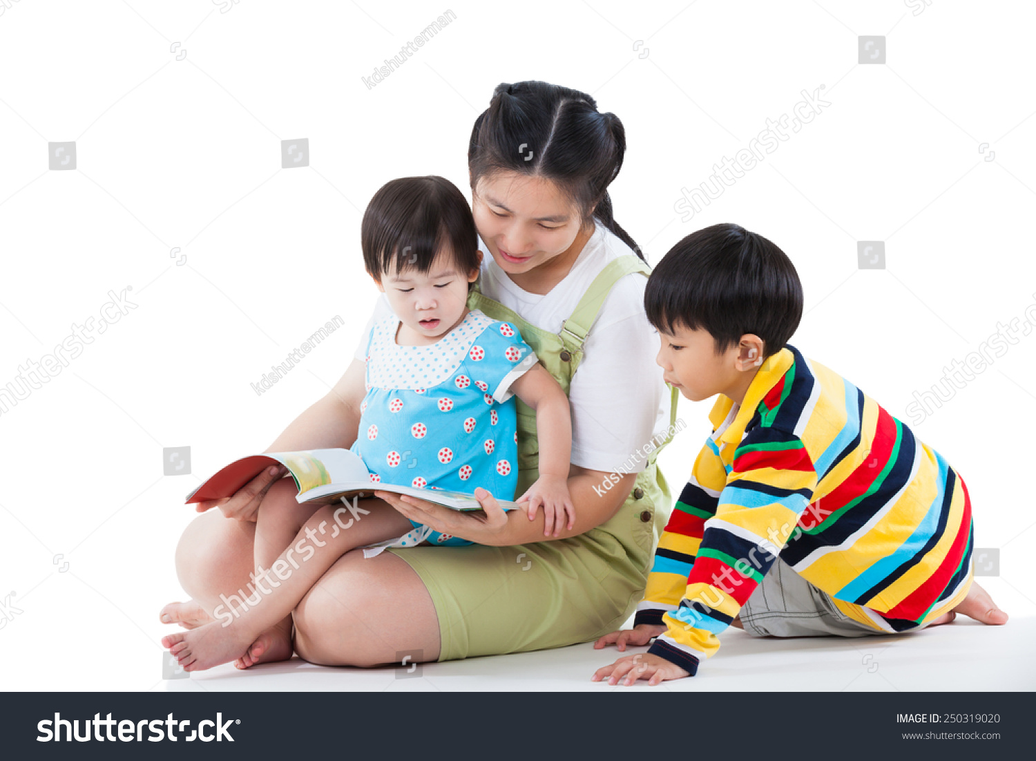 Image of cute young female with two little asian children reading a book together daughter sitting on the lap son sitting on the floor happy family concept isolated on white background