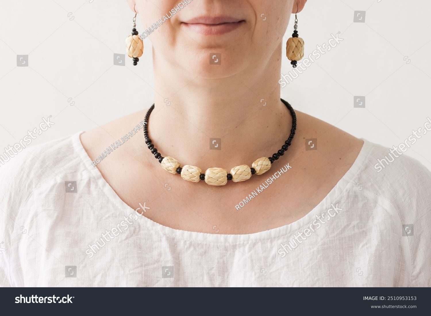 A girl with a necklace and earrings made of a black beads and straw. Trendy sustainable fashion accessories. Small depth of field 