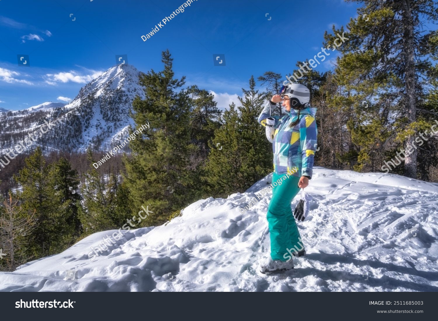 Young Woman skier standing on the snow and looking in to distance mountains and forest in background Montgenevre ski village France Alps