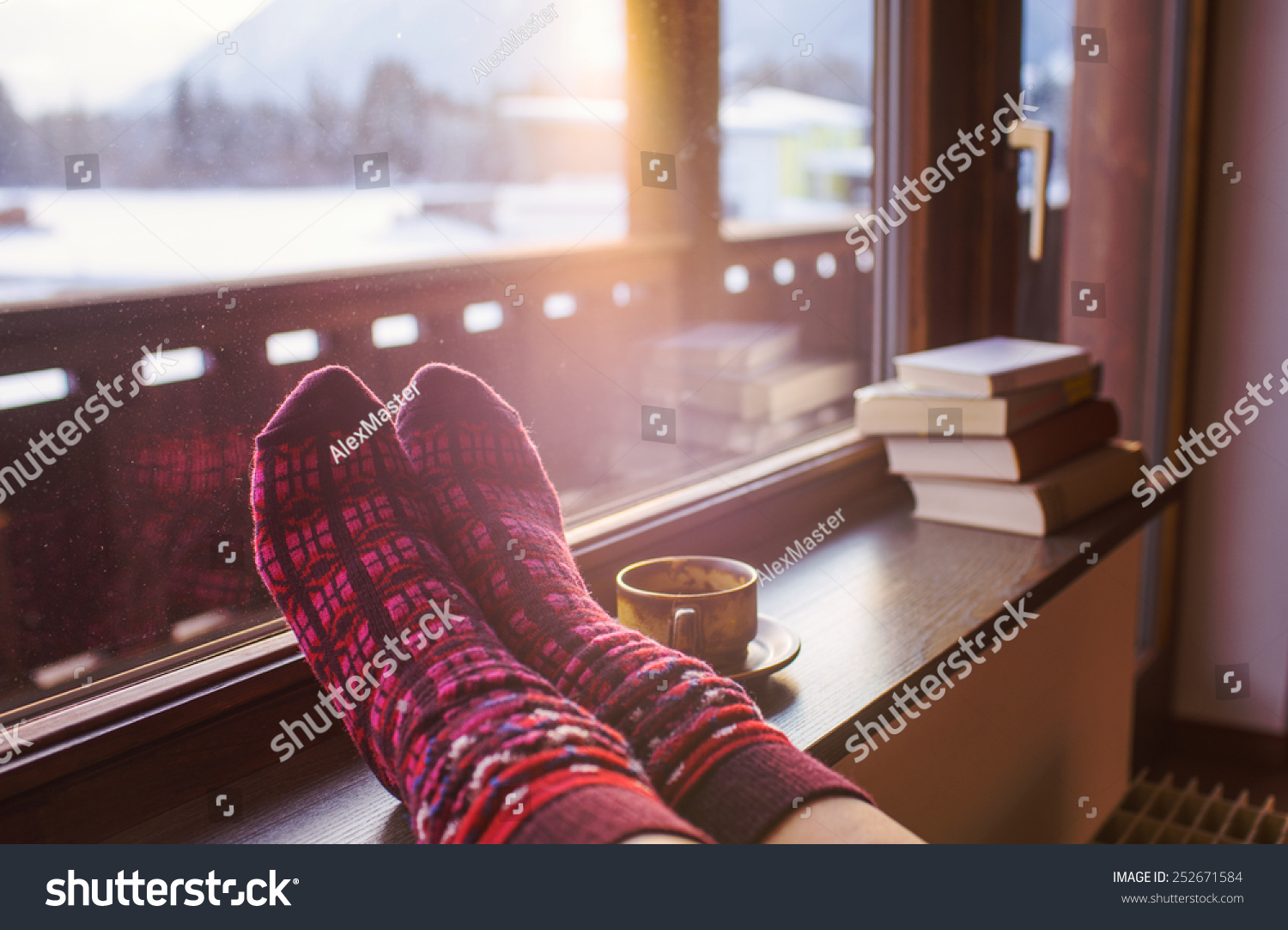 Feet in woollen socks by the Alps mountains view. Woman relaxes by mountain view with a cup of hot drink. Close up on feet. Winter and Christmas holidays concept.