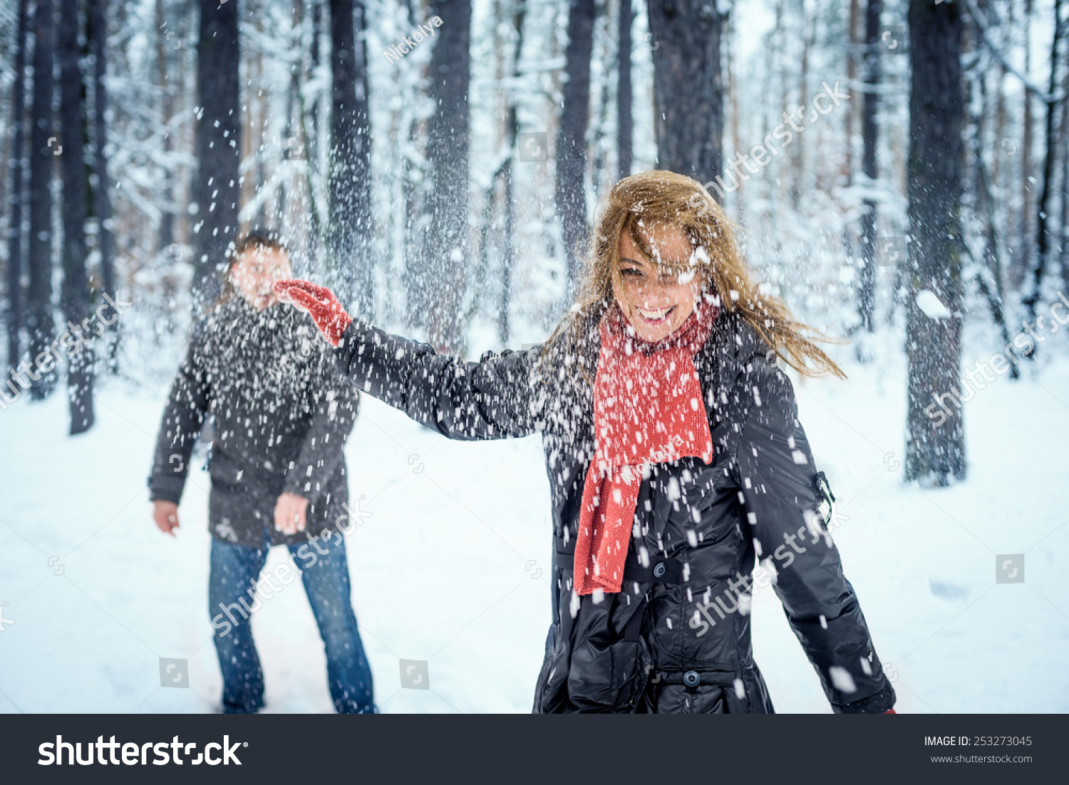 Winter couple having fun playing snowball fight