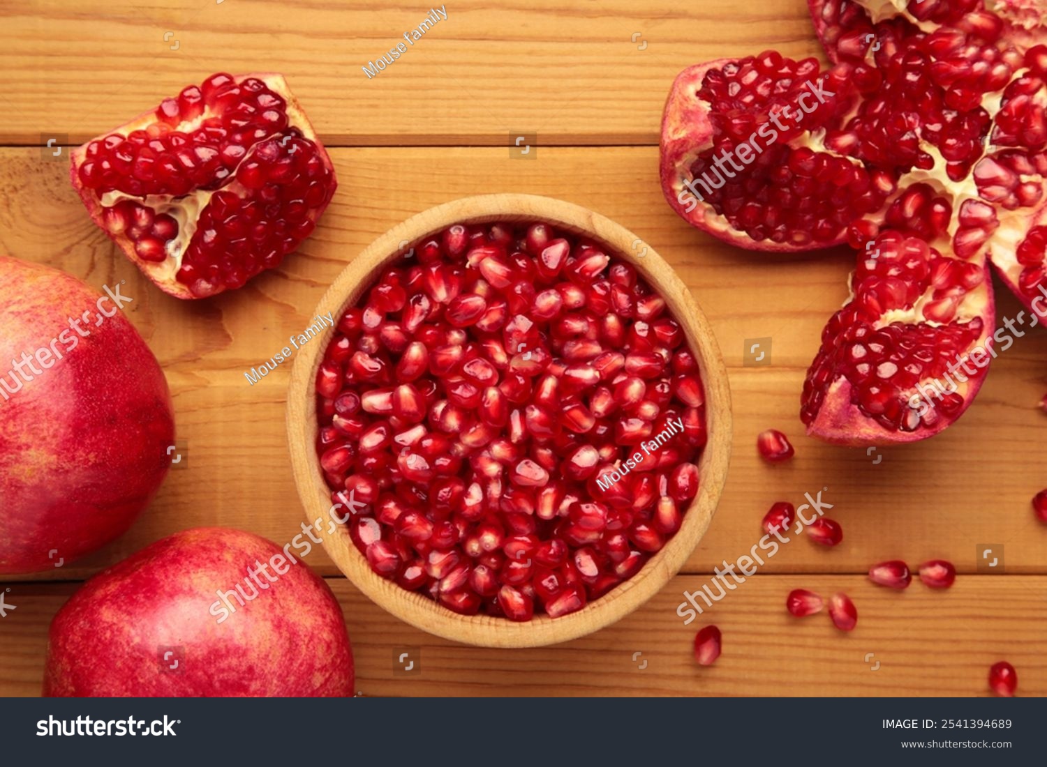 Open pomegranates  and pomegranate seeds on wooden background. Top view
