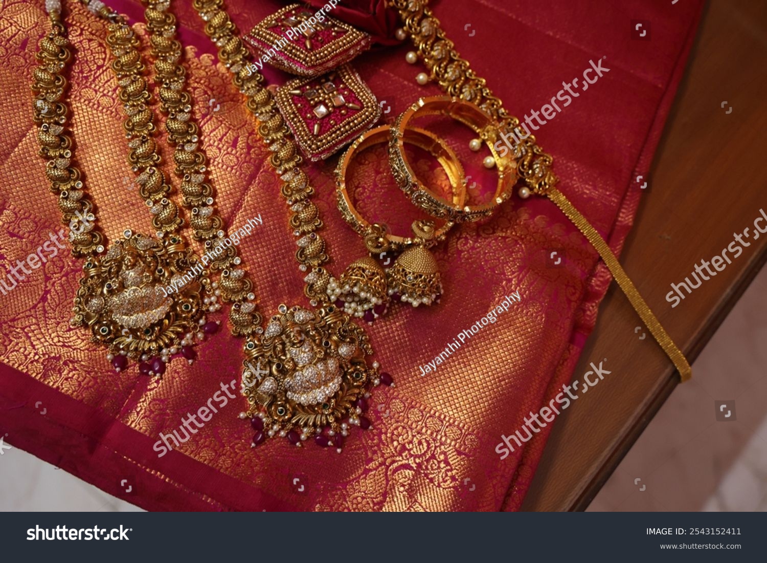multiple gold chain and necklaces placed on red silk saree. indian Bridal gold jewelry collection. antique gold jewels