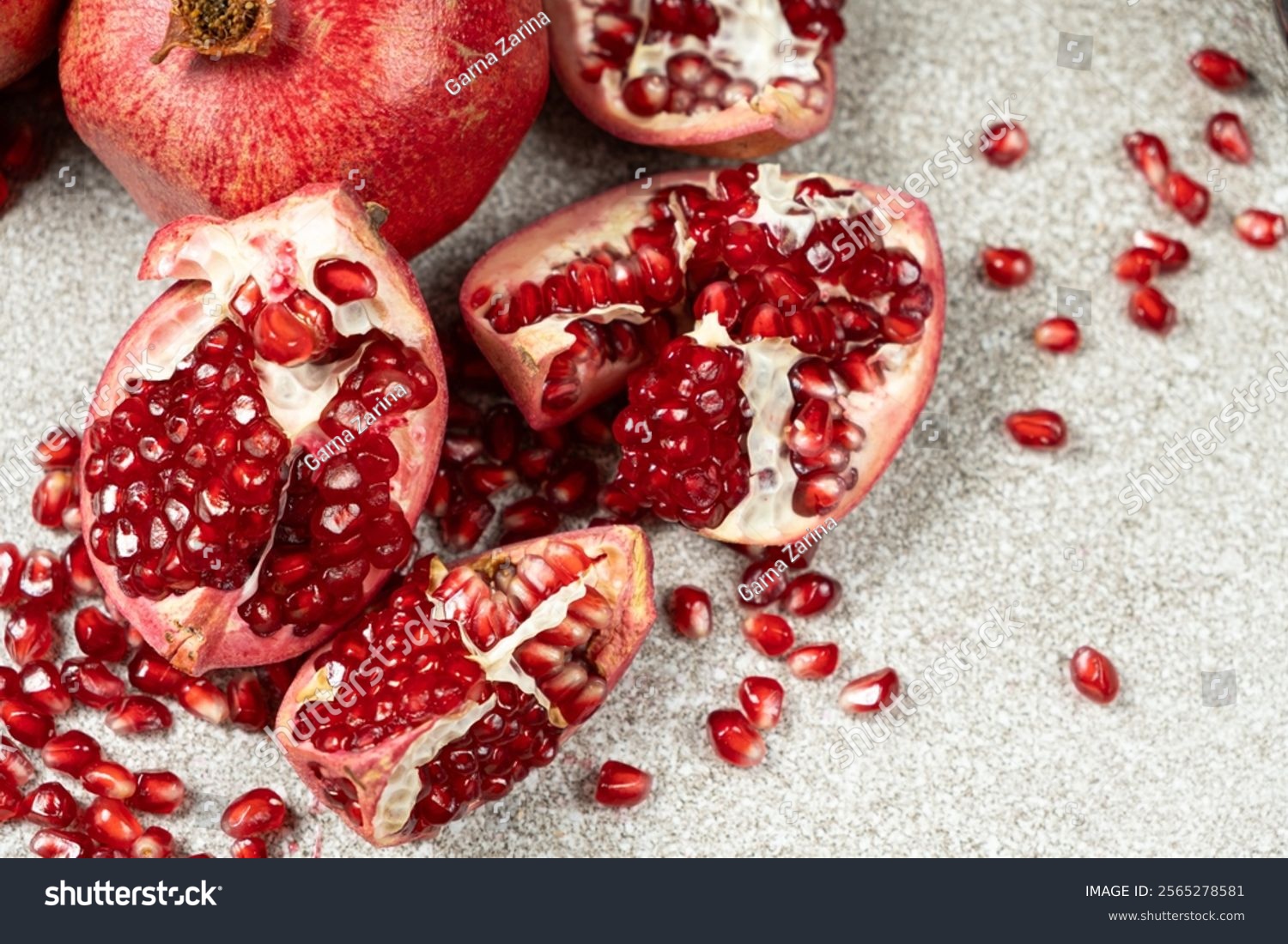 Pomegranate Seeds and Pomegranates on a Stone Gray Background Close-up.