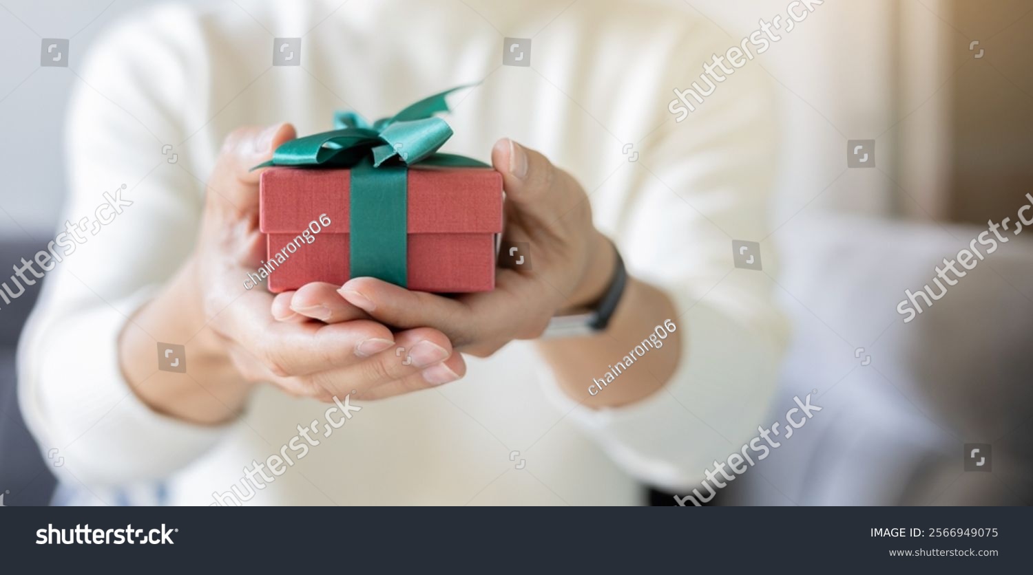 close up young man hand hold red gift box with green ribbon to send to someone special in festive season for people lifestyle concept