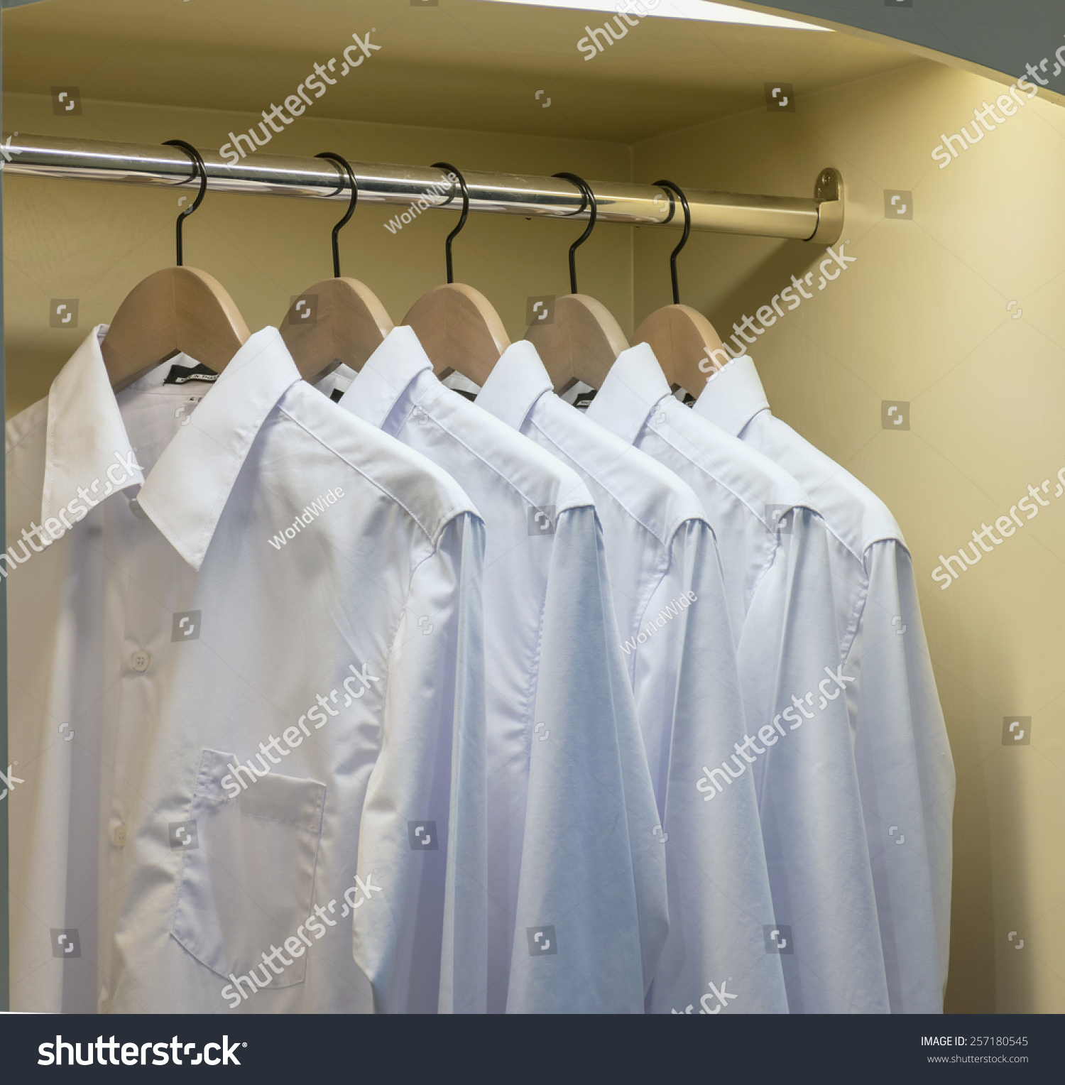 rowofwhiteshirtshangingoncoathangerinwardrobe