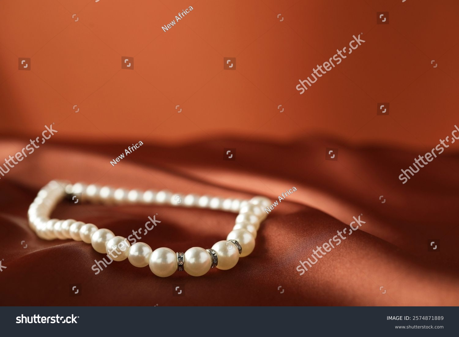 Beautiful pearl necklace on brown silk  closeup. Space for text