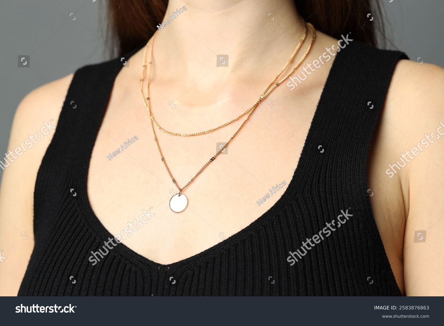Woman wearing layered golden necklace on grey background  closeup