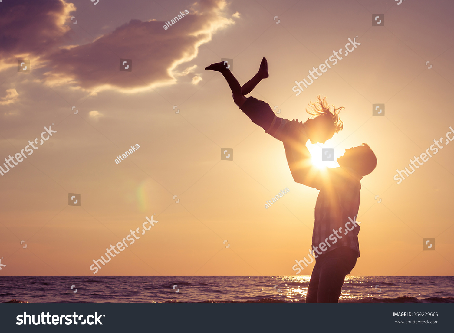 Father and son playing on the beach at the sunset time. Concept of friendly family.