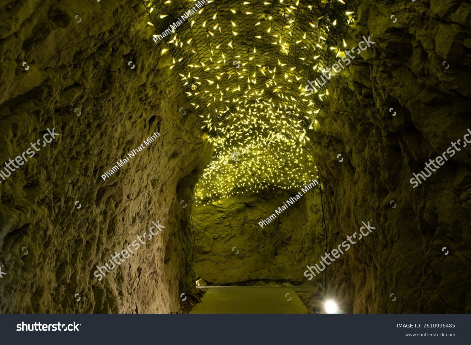 Deep within the Enoshima Iwaya Caves  a tunnel of ancient stone pulses with the golden shimmer of artificial fireflies. Lights like drifting stardust cling to the rocky ceiling  illuminating the path 