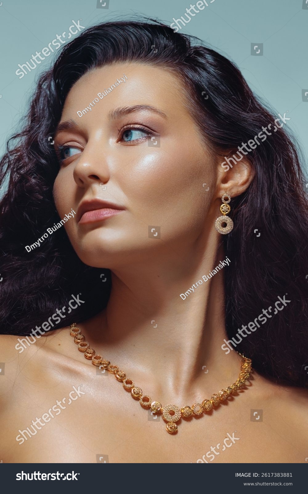 Glamorous studio portrait of a confident woman with wavy hair  glowing skin  and luxurious gold necklace and earrings. Ideal for fashion  jewelry ads  and beauty campaigns.